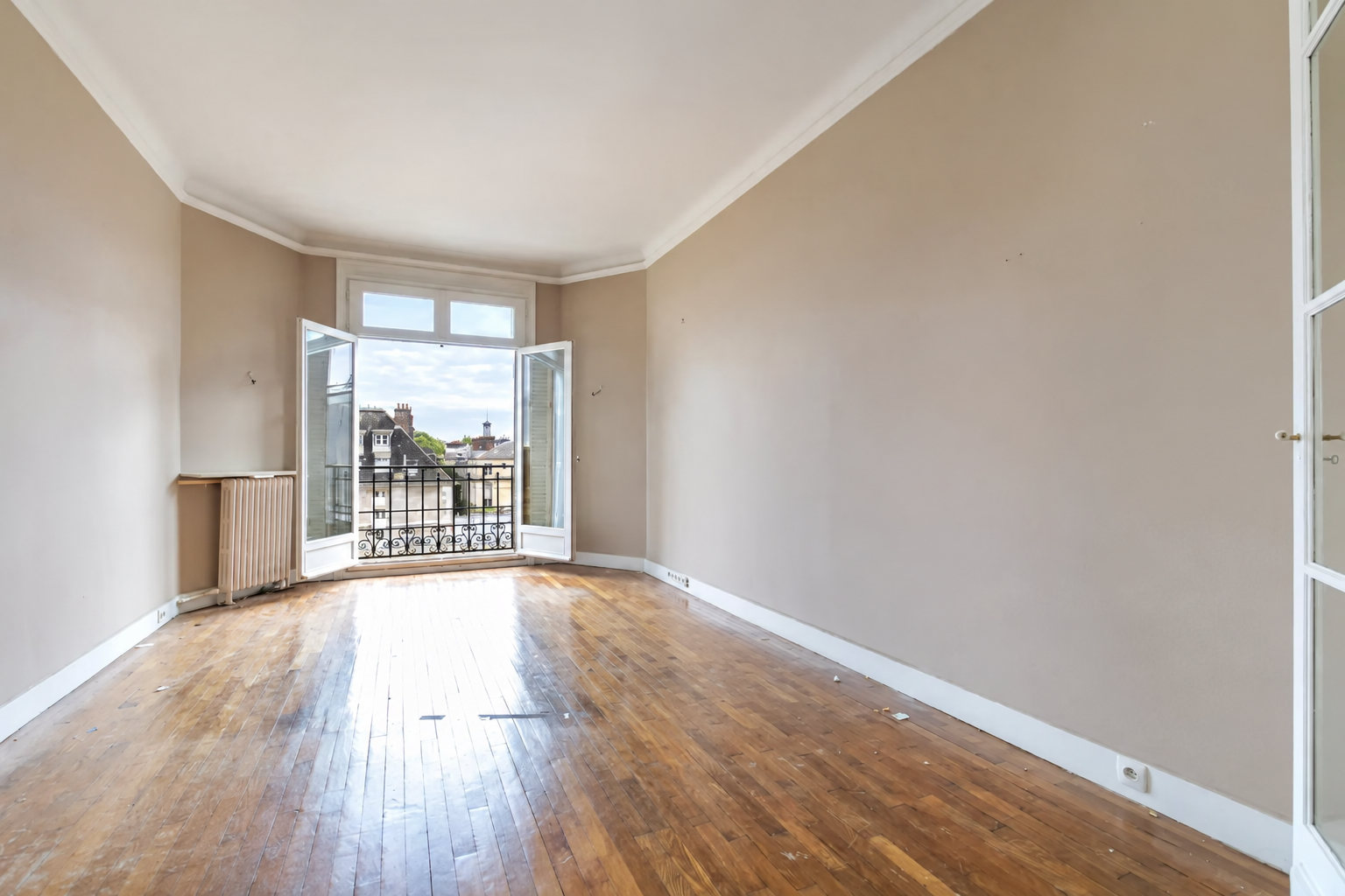Chambre spacieuse avec parquet et vue sur les toits