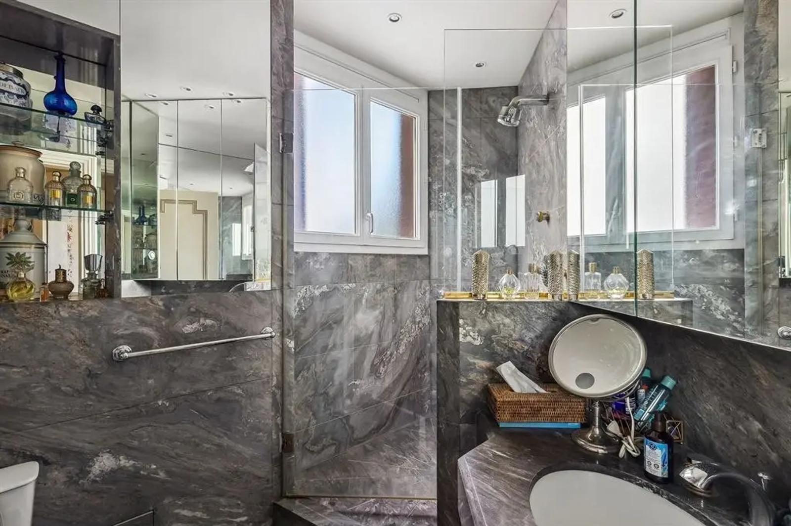 Salle d’eau en marbre avec paroi vitrée et miroirs