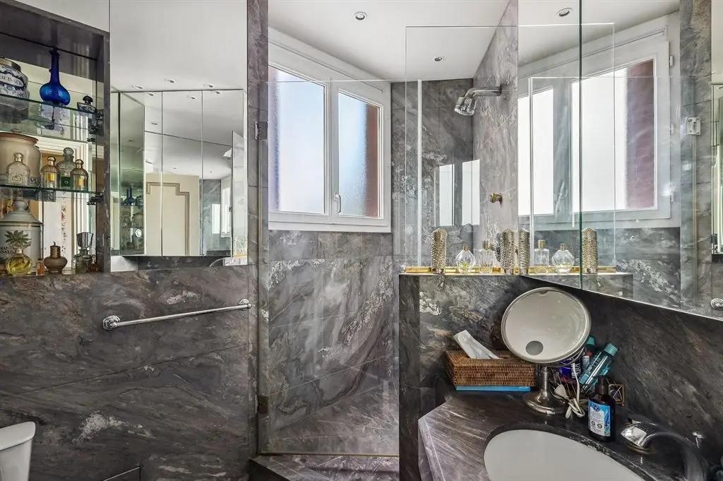 Salle d’eau en marbre avec paroi vitrée et miroirs