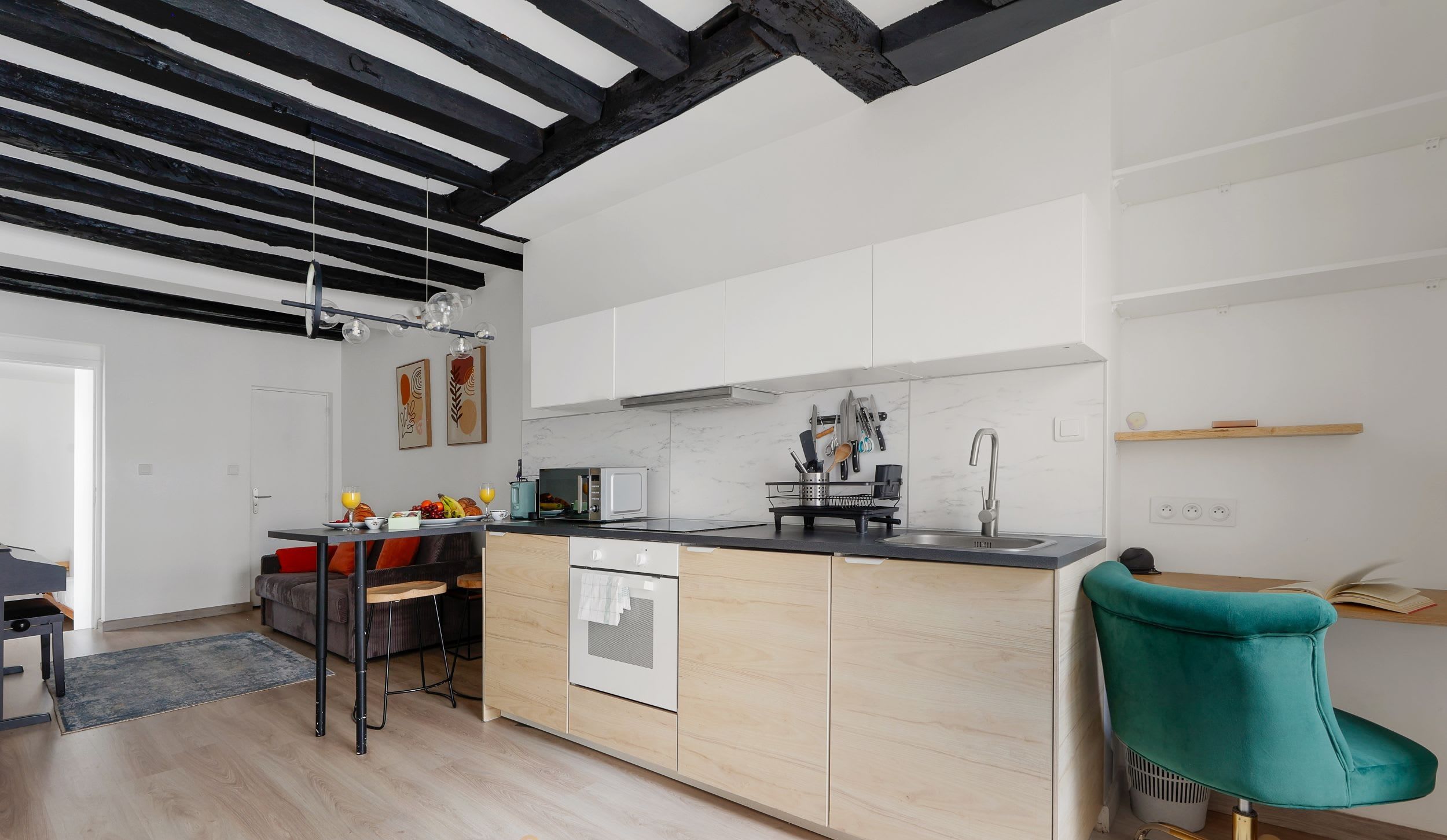 Appartement meublé rue Saint-Séverin Paris 5e, canapé-lit sous des poutres apparentes dans un intérieur du Quartier Latin