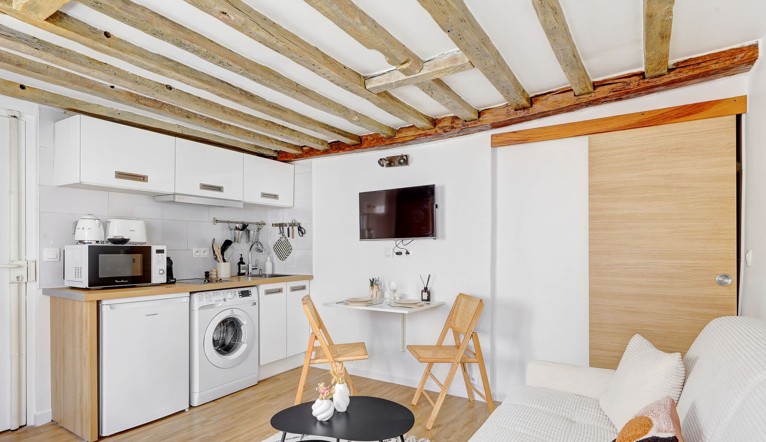 Welcome to our living room, open onto the kitchen, featuring a comfortable sofa bed, a dining corner and a TV.