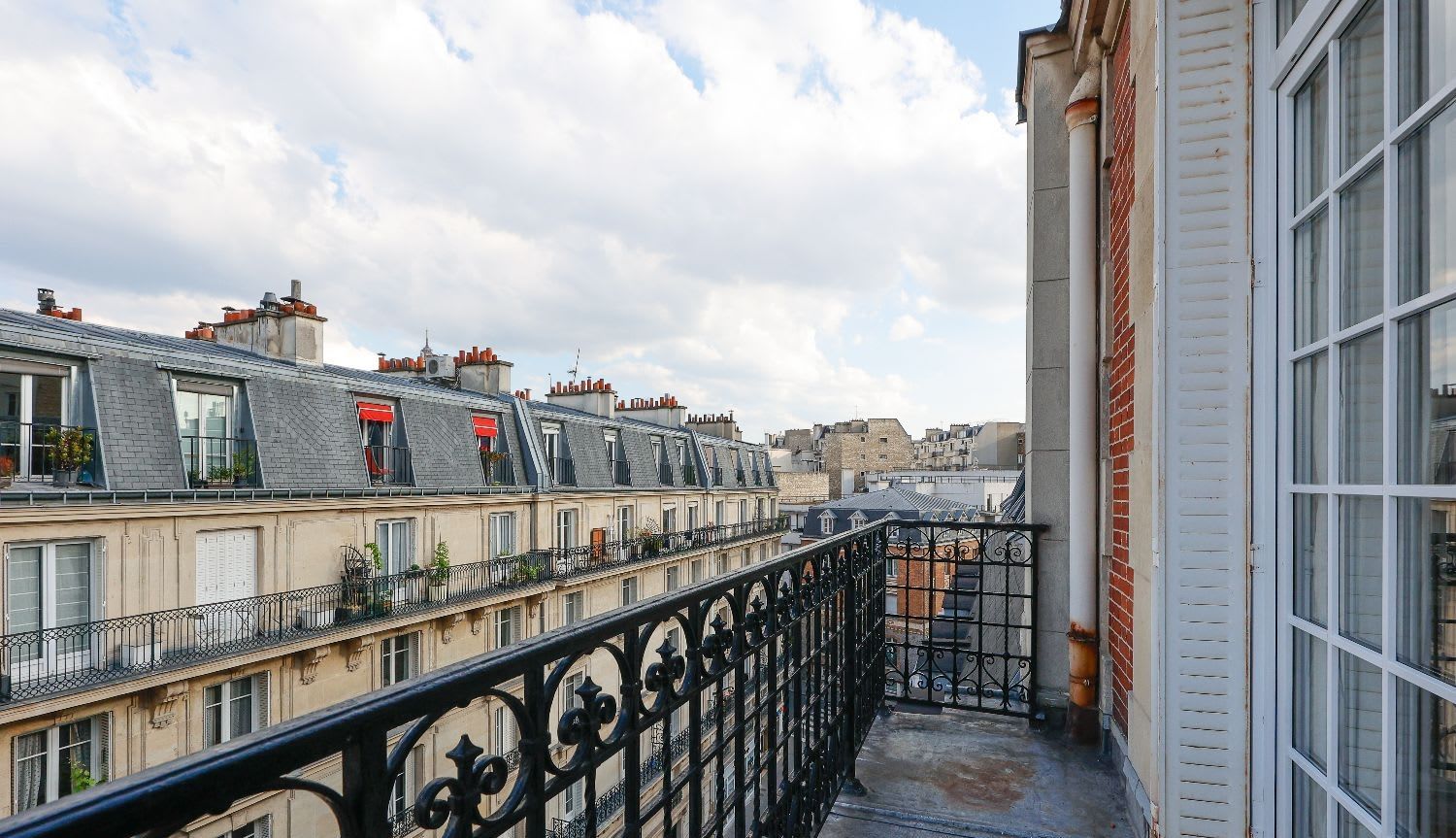 Duplex de luxe Paris 16e, séjour double hauteur avec balcon en fer forgé et vue Tour Eiffel, location meublée moyenne durée