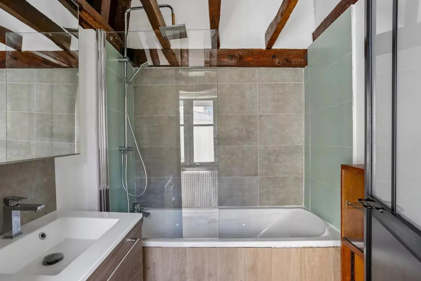 Salle de bains avec baignoire et poutres apparentes