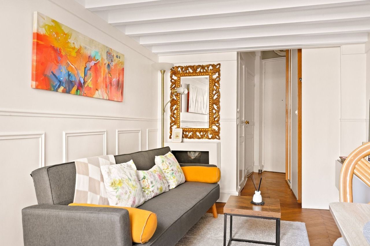 Séjour lumineux avec canapé, cheminée décorative et miroir doré dans un duplex rue Montmartre, Montorgueil, Paris 2e