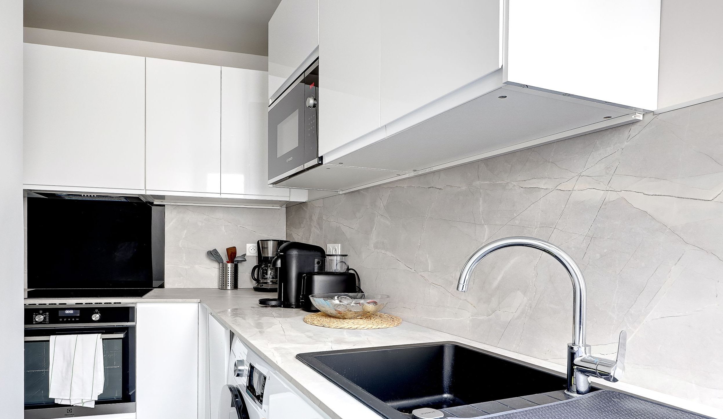 This bright, fully equipped kitchen has everything you need for a pleasant stay, including a toaster, microwave, stovetop, kettle, and even a washing machine for your convenience.