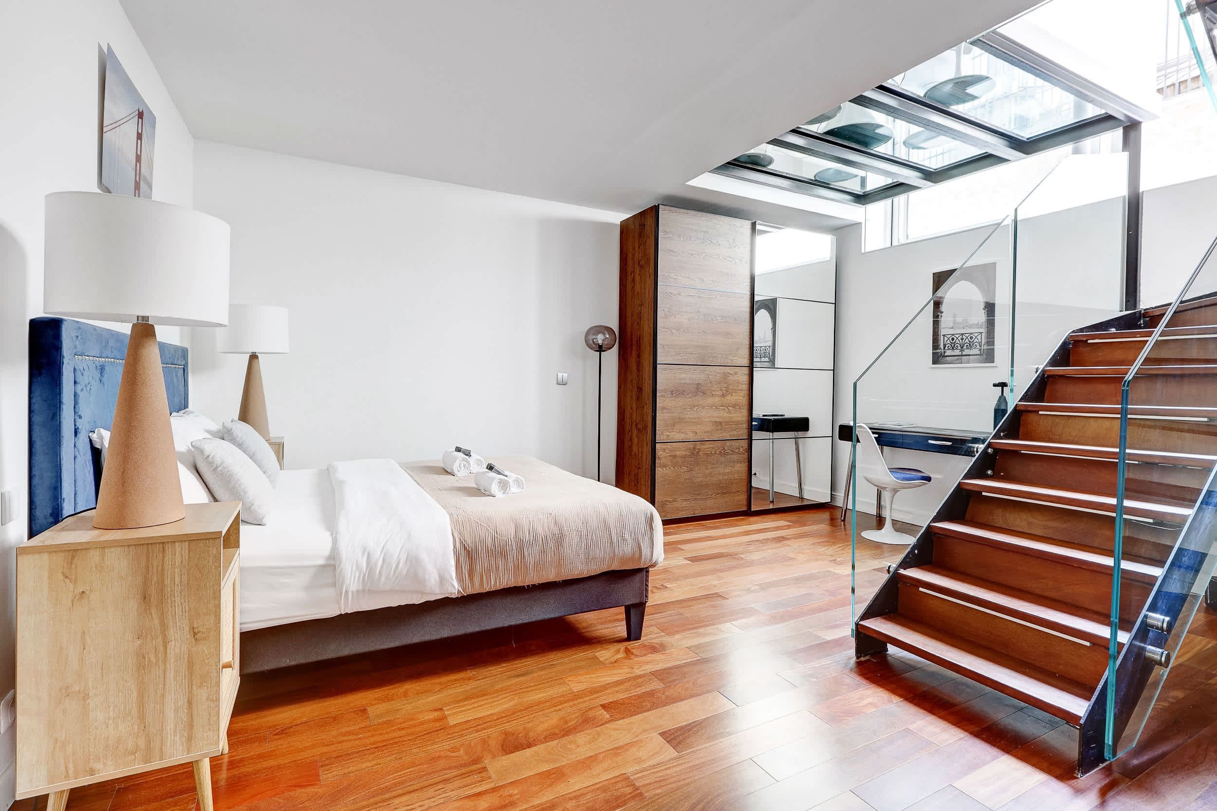 Bright bedroom with a desk area and staircase.