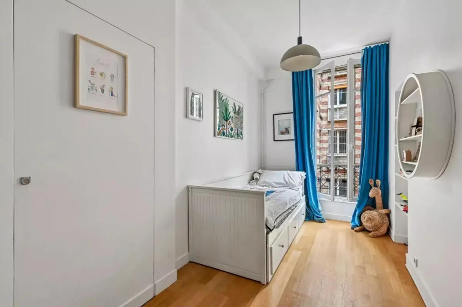 Chambre d’enfant avec rideaux bleus et parquet