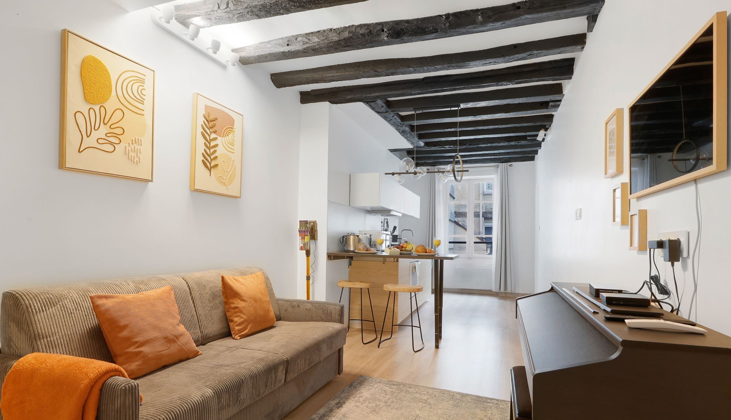 Appartement meublé rue Saint-Séverin Paris 5e, canapé-lit sous des poutres apparentes dans un intérieur du Quartier Latin