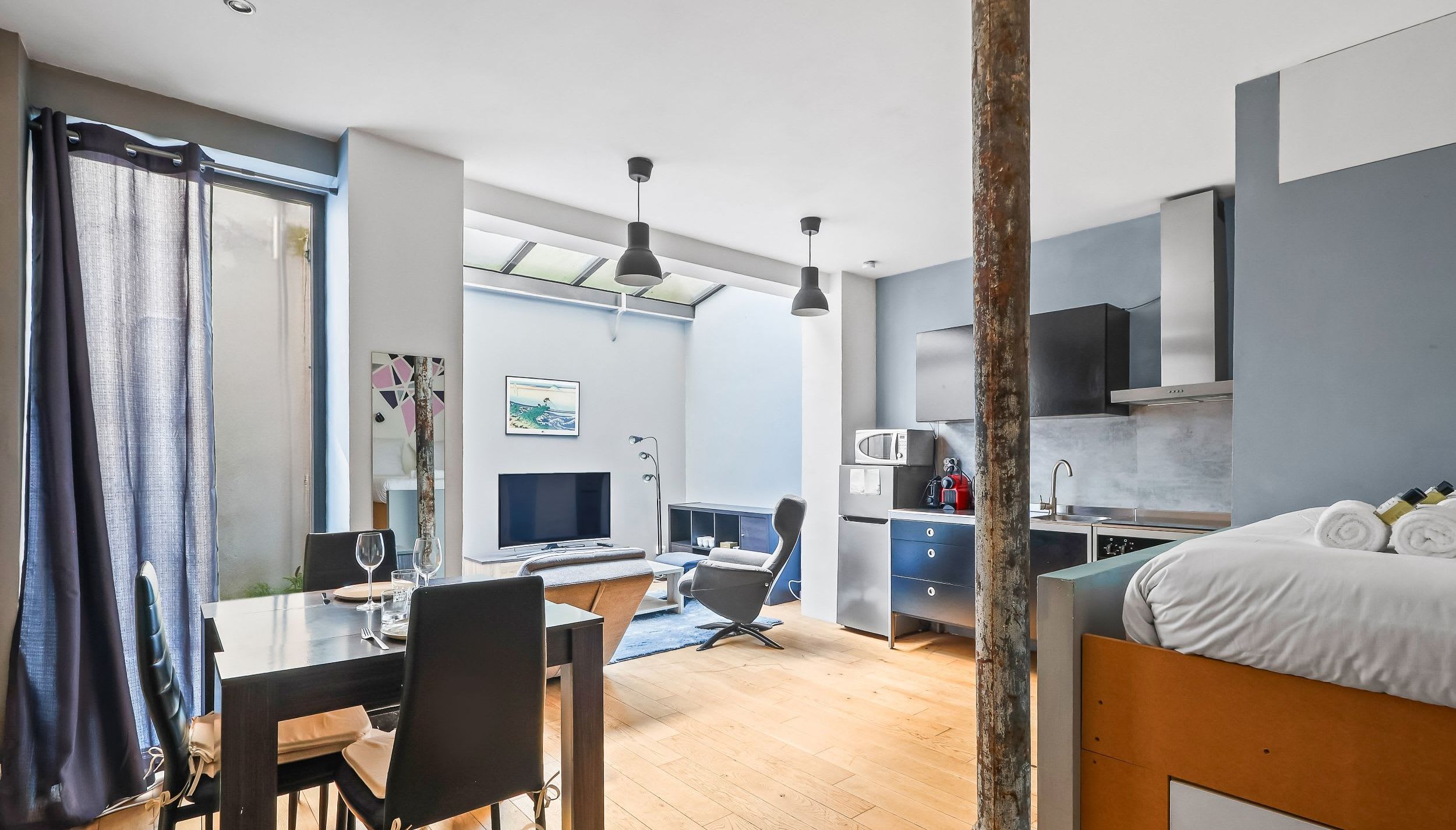 Loft design avec verrière type atelier et mur en pierre apparente Paris 11e, espace de vie lumineux avec mezzanine près d'Oberkampf