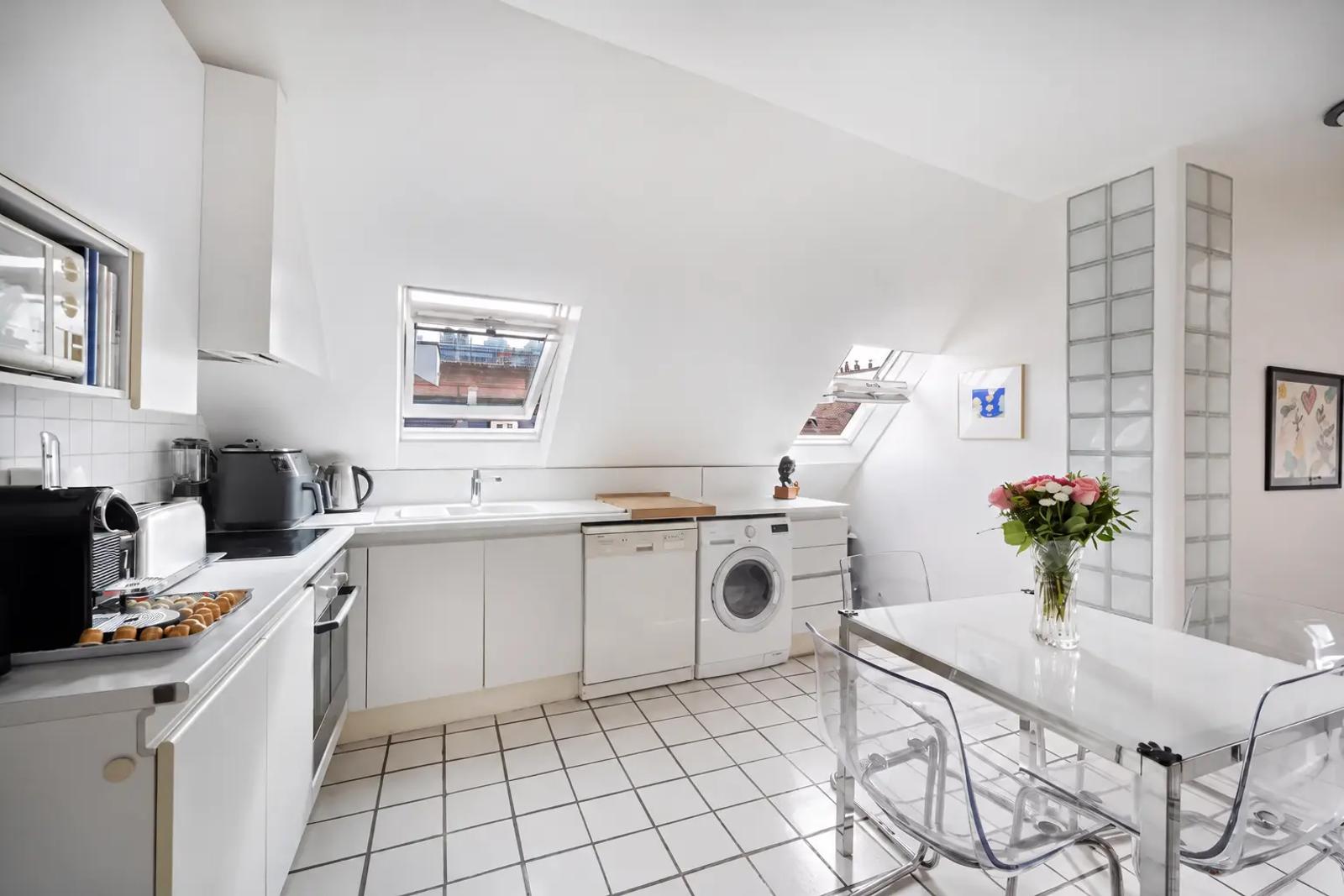 Cuisine blanche avec coin repas et fenêtres de toit