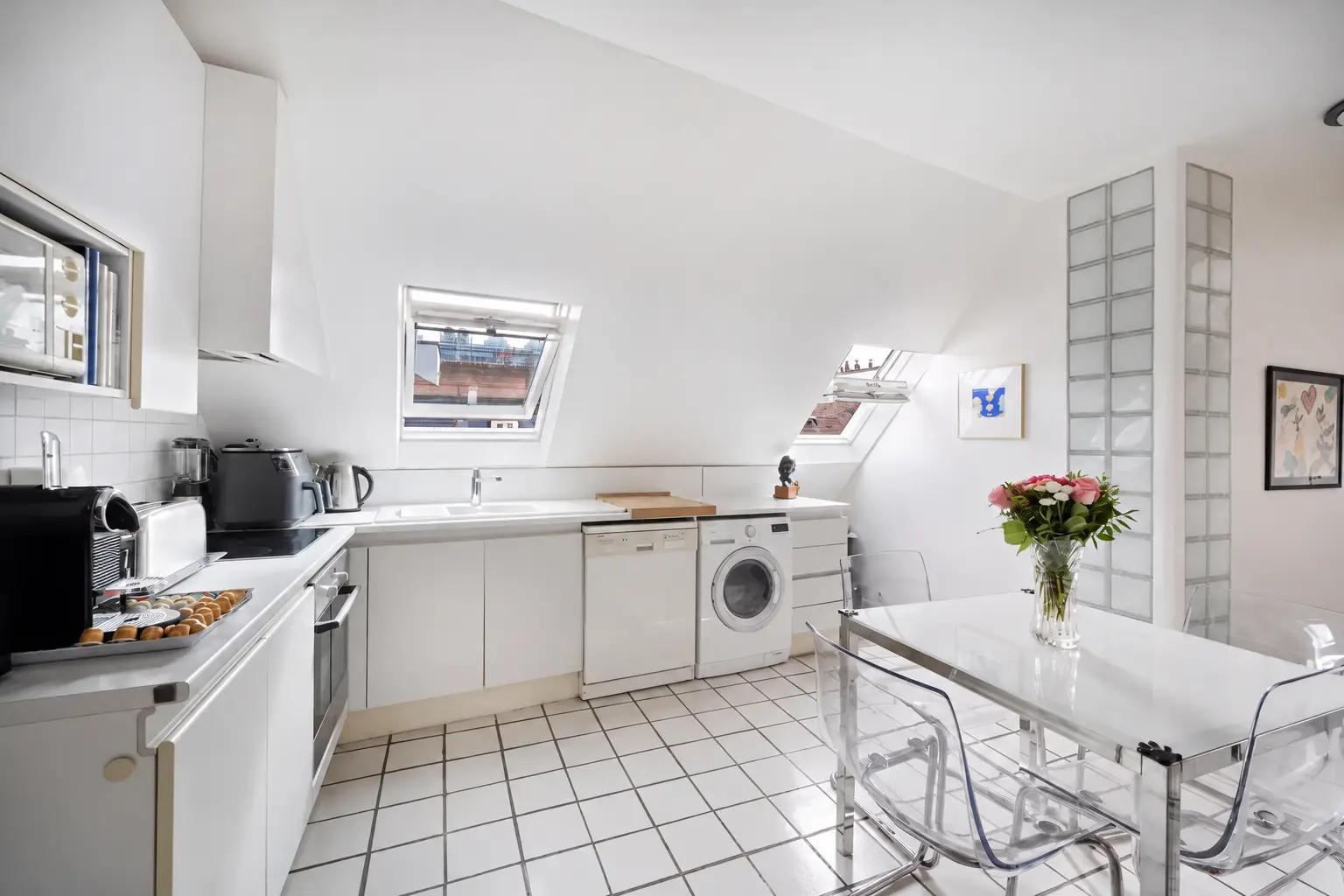 Cuisine blanche avec coin repas et fenêtres de toit