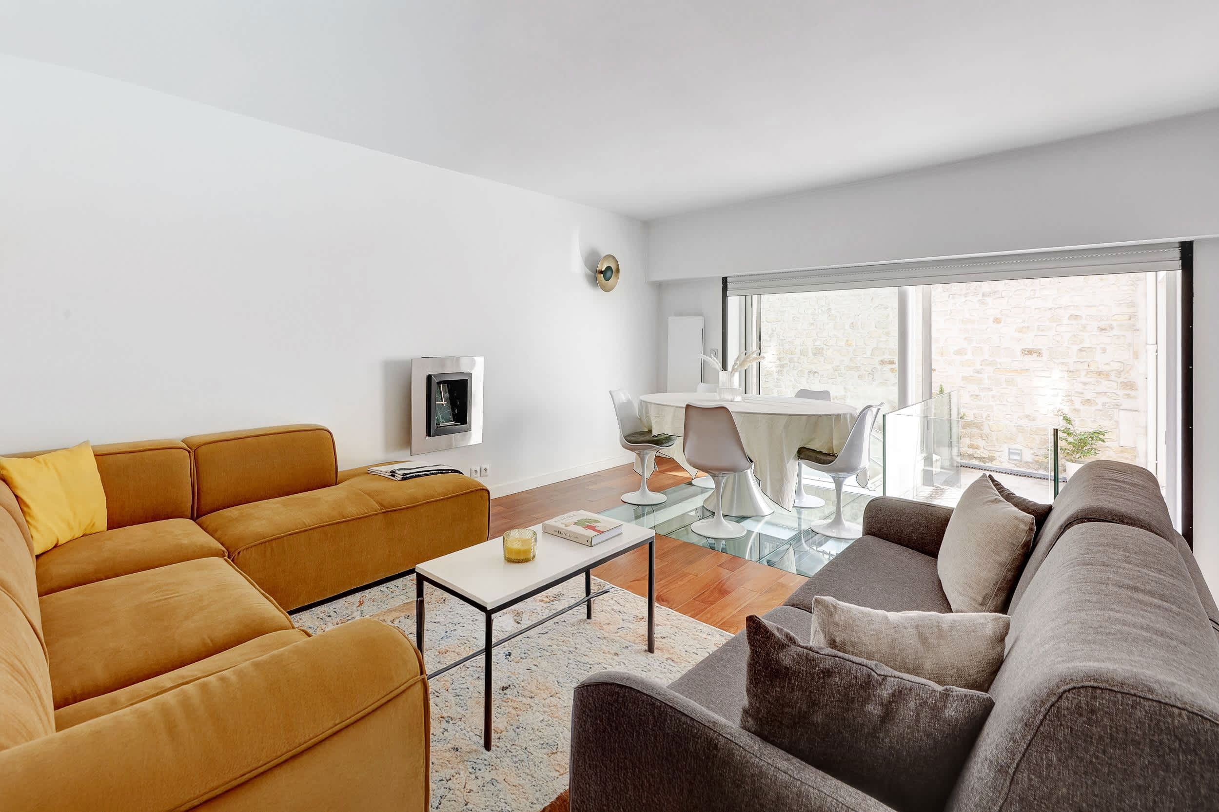 Bright architect-designed Paris apartment with a glass roof, modern open living space, sofa, and open kitchen.