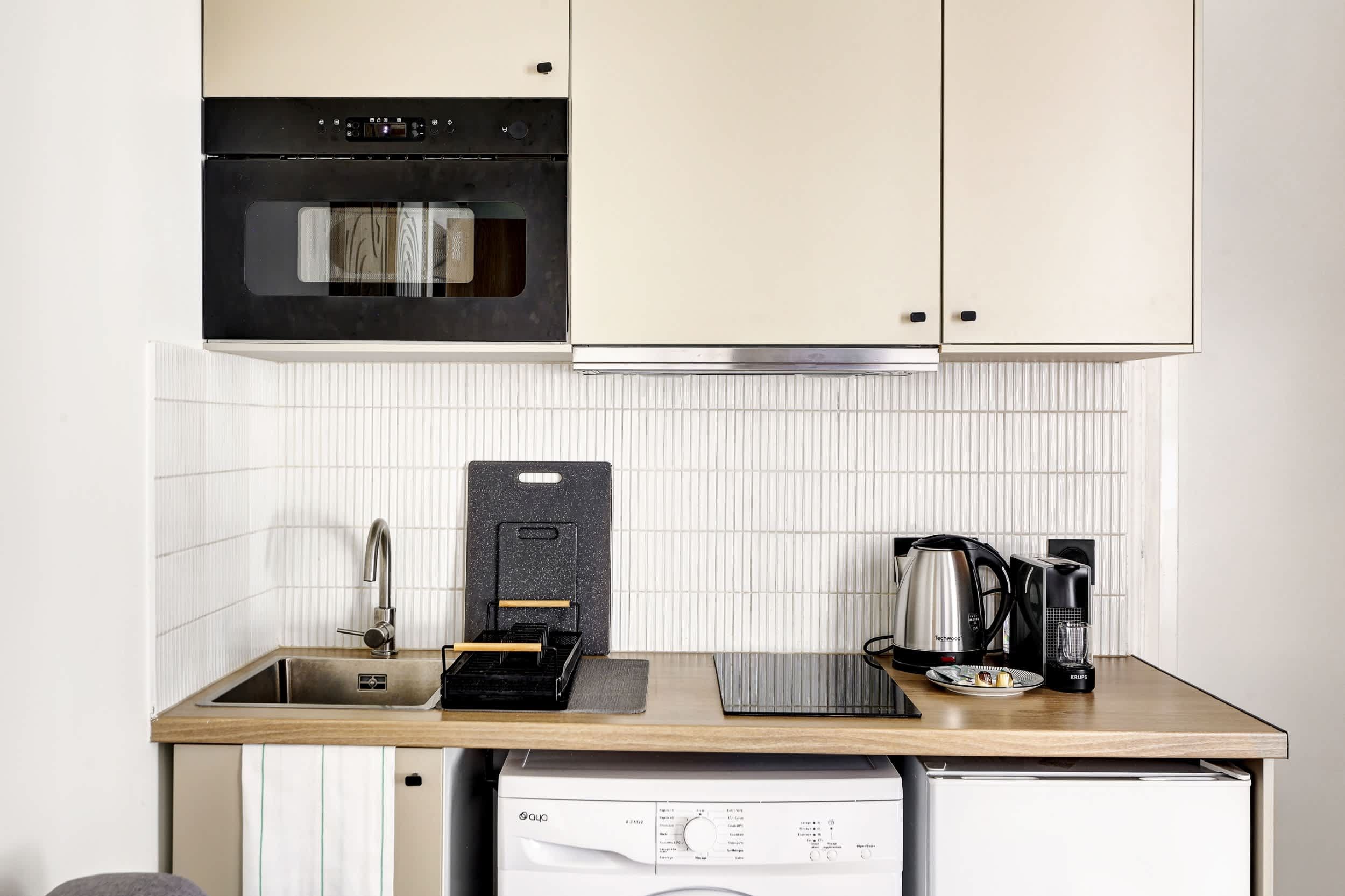 Kitchenette fonctionnelle et équipée : machine à café, micro-ondes, rangements, plaques, etc.