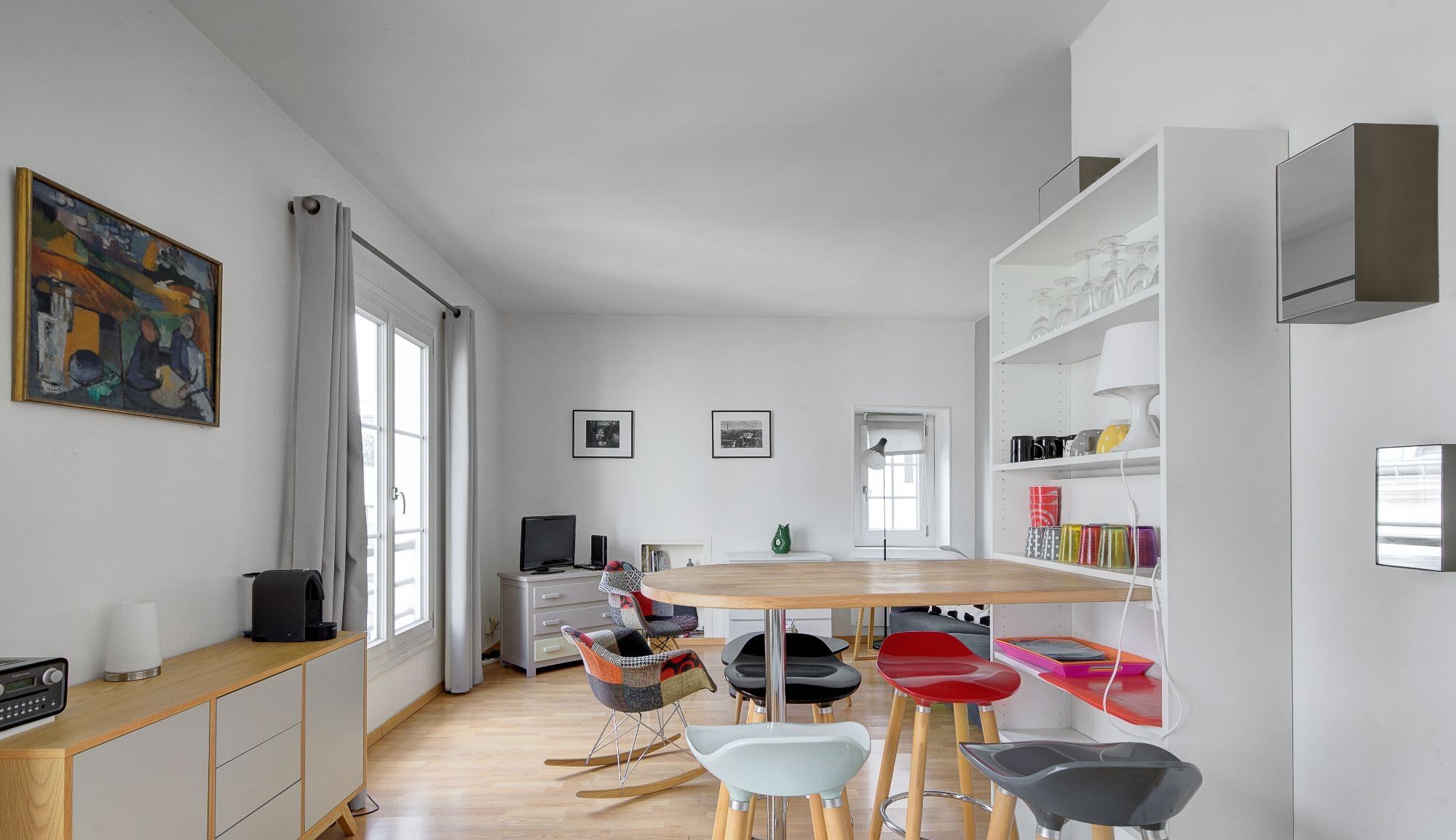 Boho-chic furnished apartment rue Vieille du Temple Marais Paris 4th, bright living room with patchwork armchairs and rooftop views