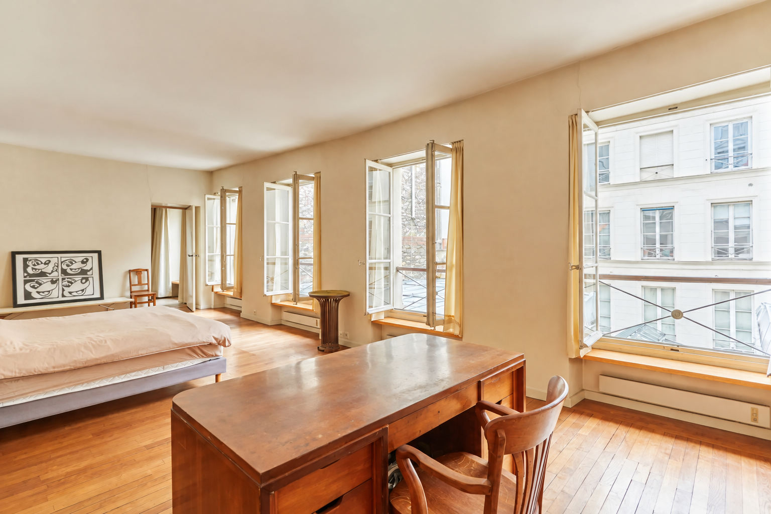Chambre lumineuse avec bureau et grandes fenêtres