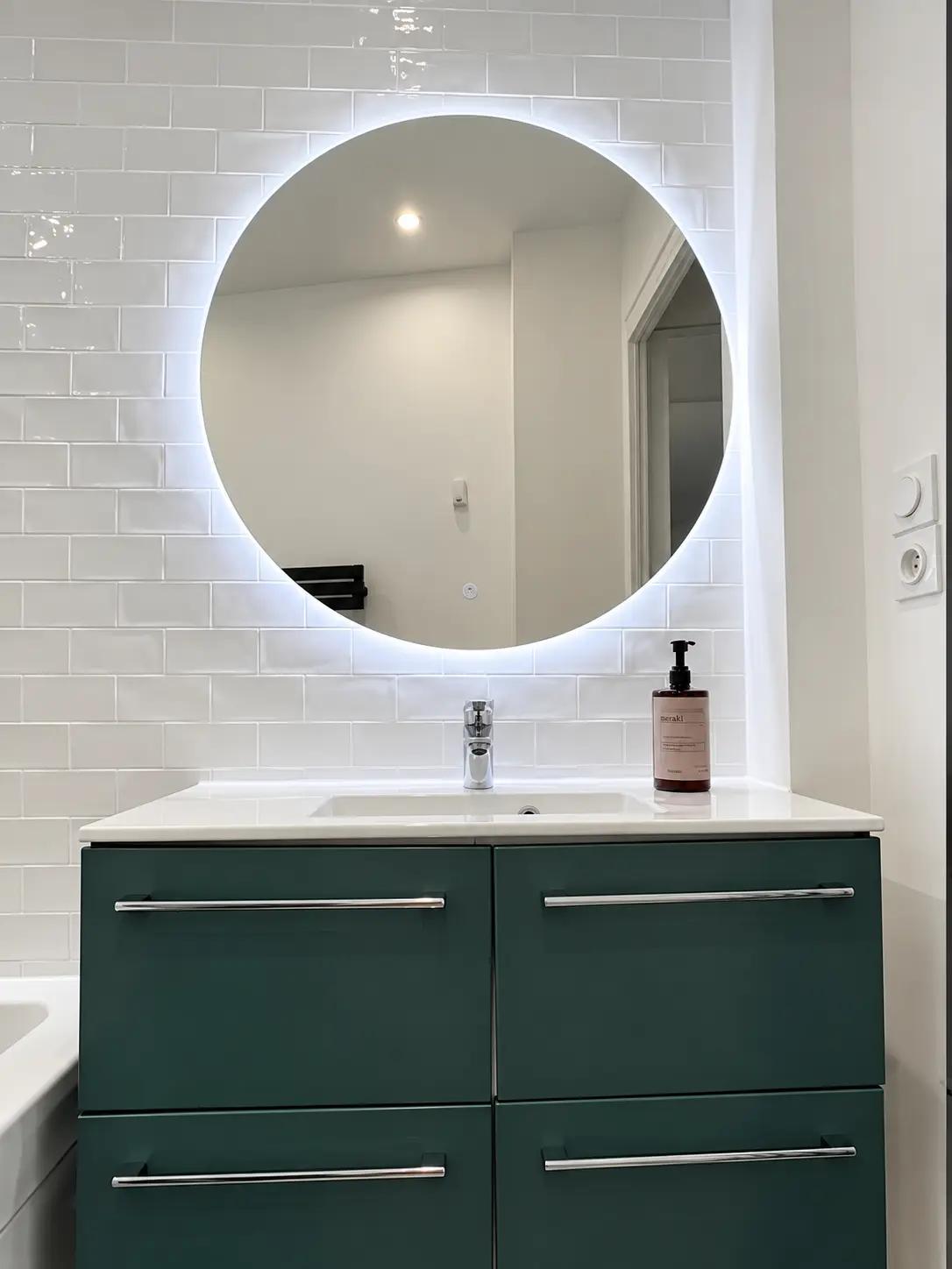 Meuble vasque moderne avec miroir rond dans une salle de bains Paris 14e