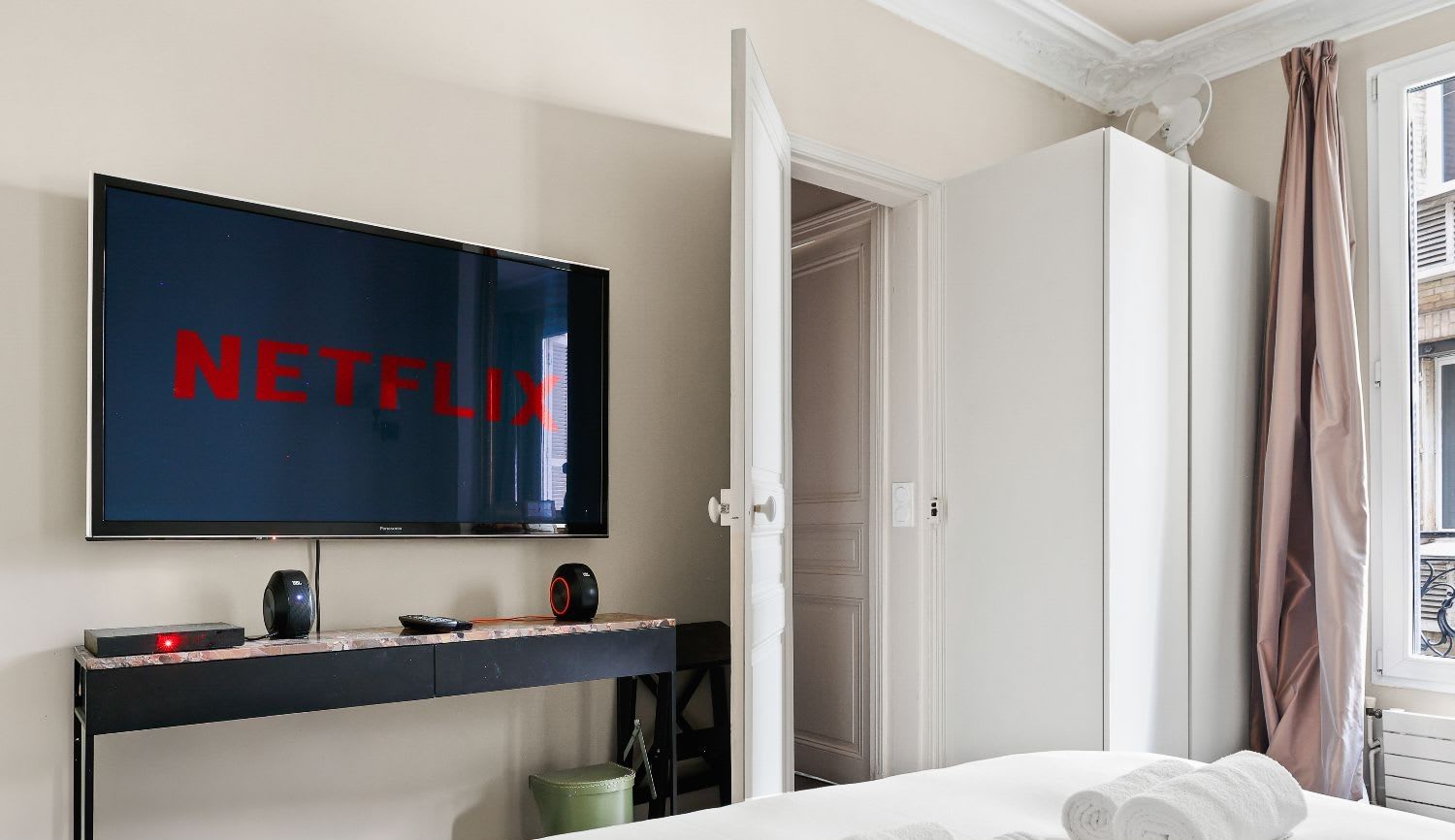 Salle à manger haussmannienne d'un appartement meublé rue Lentonnet Paris 9e, suspension Vertigo au-dessus d'une table ovale et chaises Louis Ghost sous des moulures d'époque