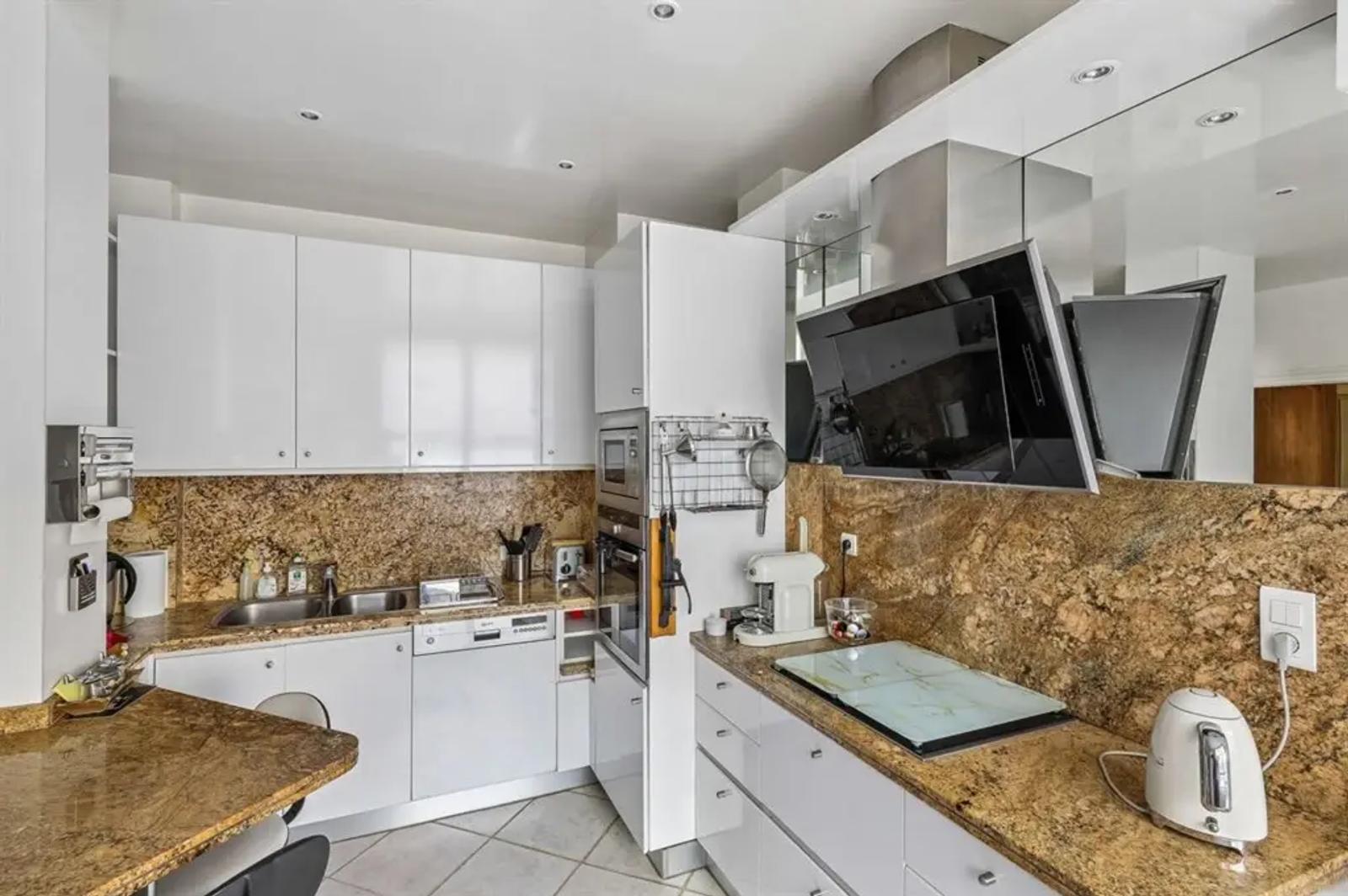 Cuisine équipée avec placards blancs et plans en pierre