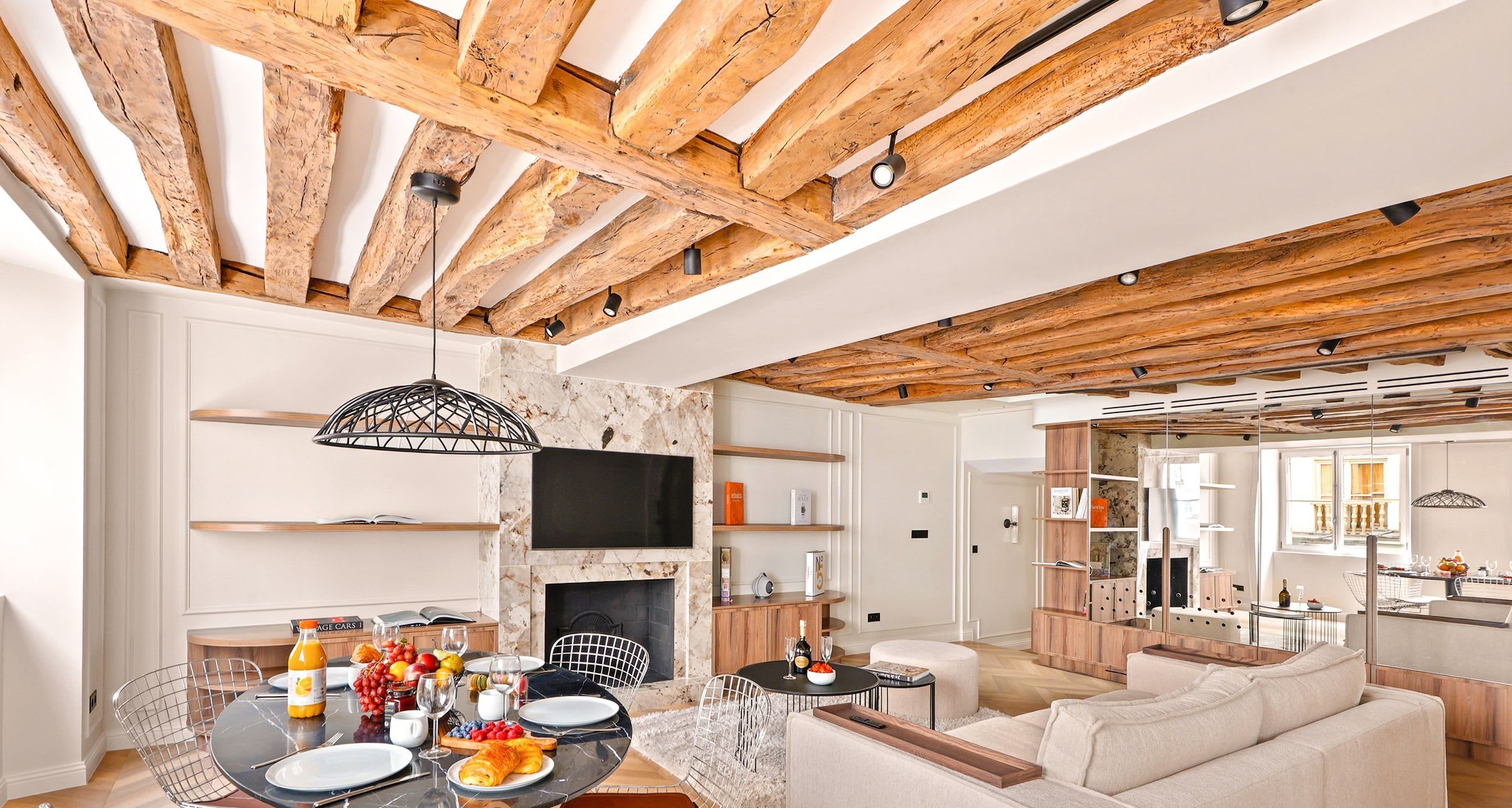 Salon avec poutres de chêne apparentes, cheminée de marbre et canapés en bouclette dans un appartement deux chambres rénové quai Malaquais, Saint-Germain, Paris 6e