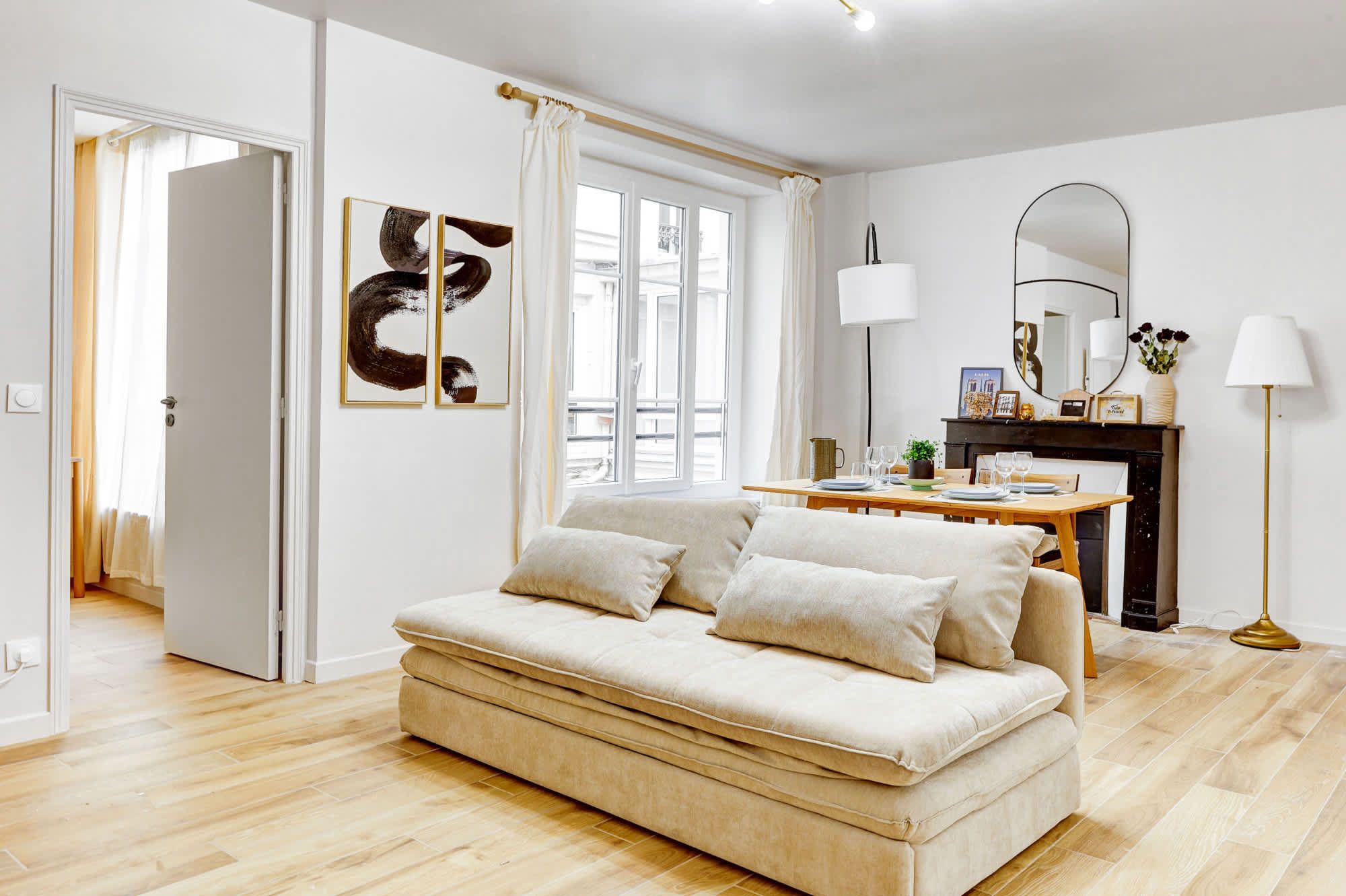 Appartement meublé rénové de 55 m² rue des Tournelles Paris 4e, canapé-lit et coin repas dans un intérieur lumineux du Marais