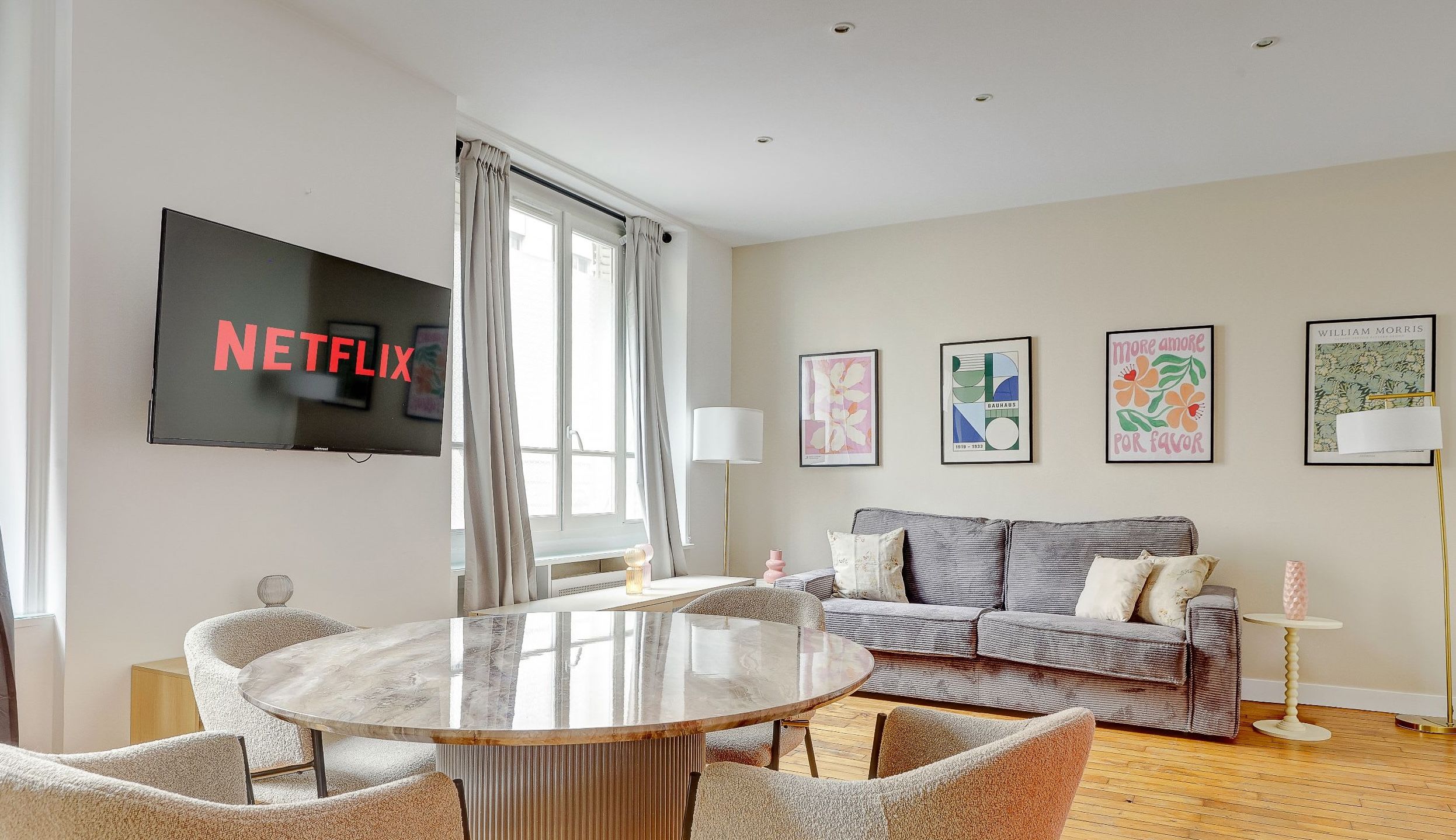 Modern Montparnasse apartment living room with convertible sofa, dining corner, and bright natural light.