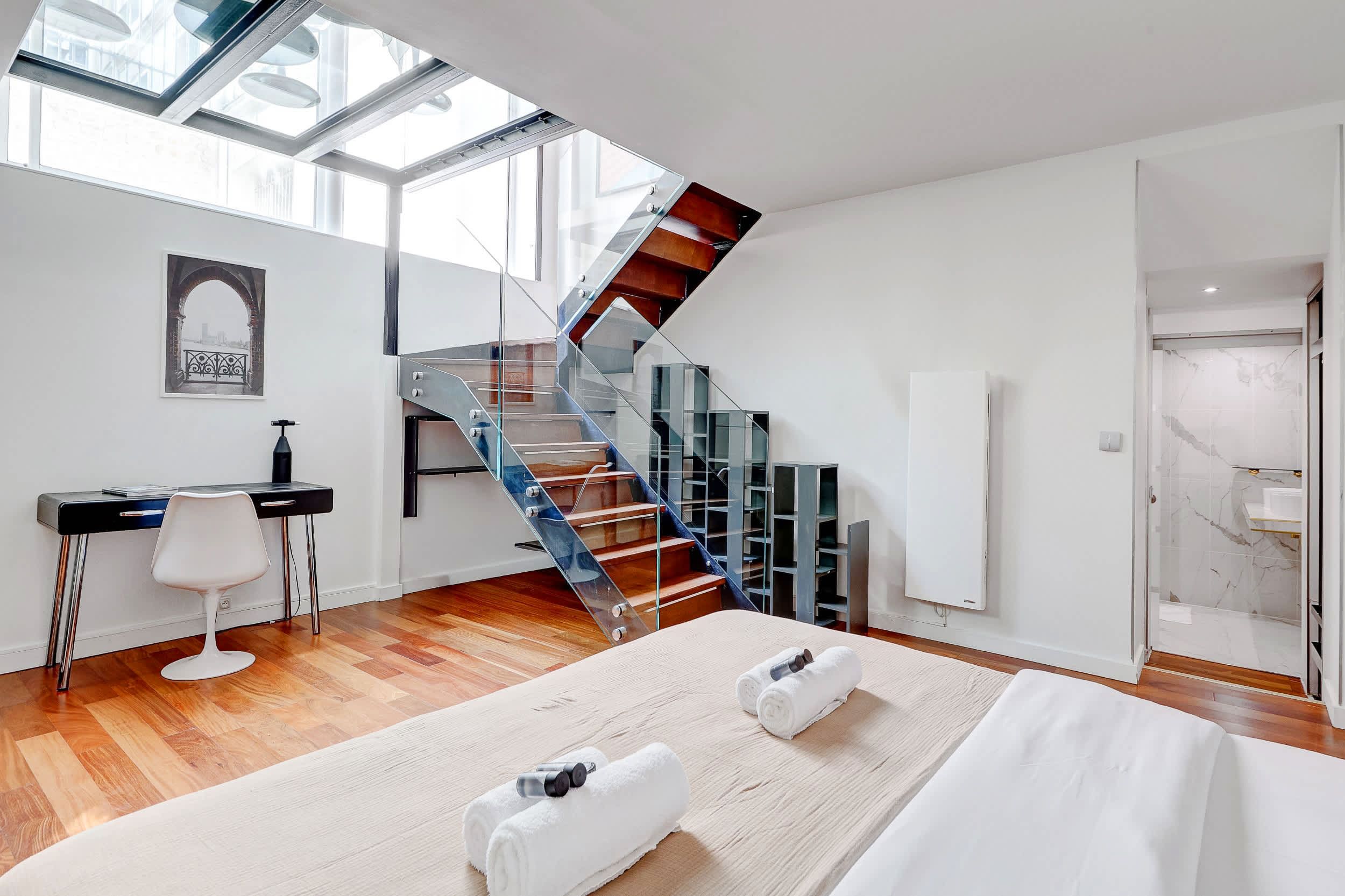 Bright bedroom with a desk area and staircase.