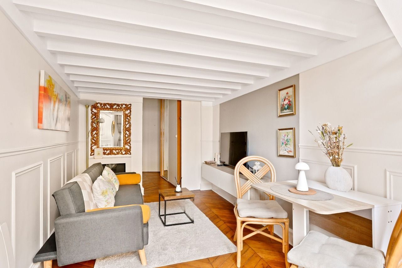 Séjour lumineux avec canapé, cheminée décorative et miroir doré dans un duplex rue Montmartre, Montorgueil, Paris 2e