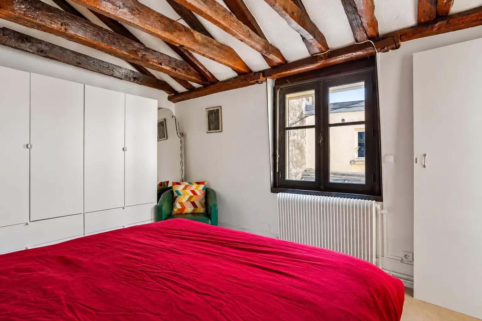 Chambre avec fenêtre sur cour et poutres apparentes