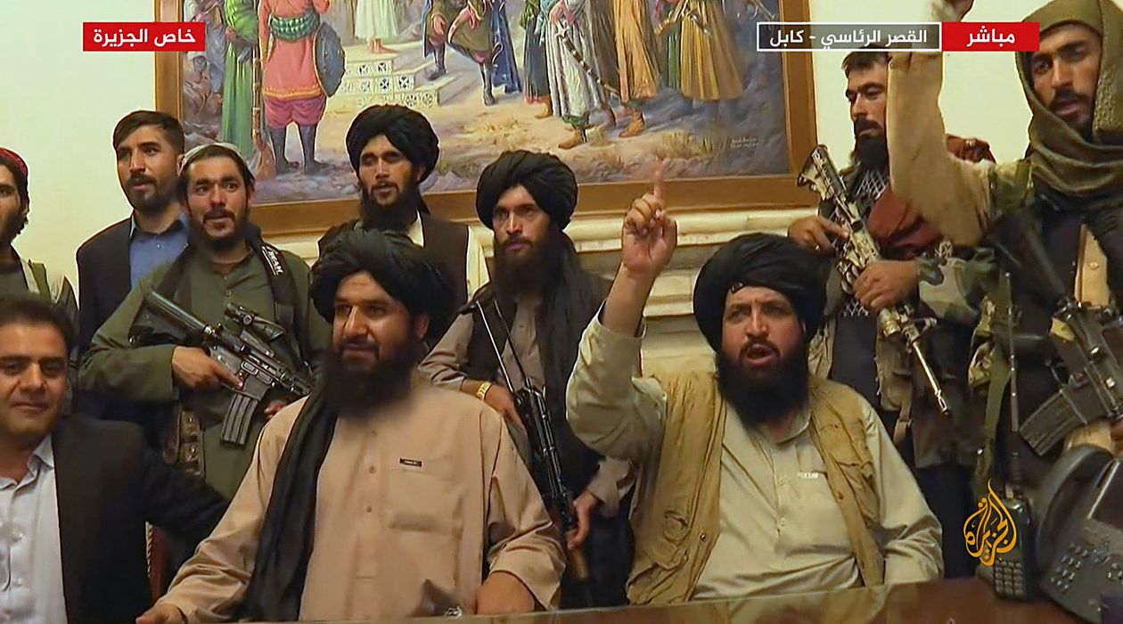 Et skjermbilde fra en nyhetssending på arabisk. Bildet viser ledere i Taliban i Presidentpalasset i Kabul. Det står flere menn med maskingevær bak lederne.