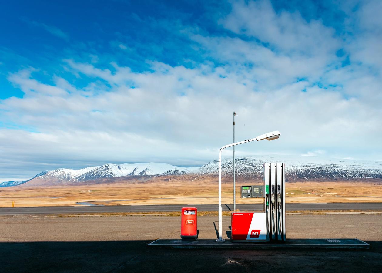 Et bilde av en enslig bensinpumpe i ødemarken. Man ser høye fjell i det fjerne.