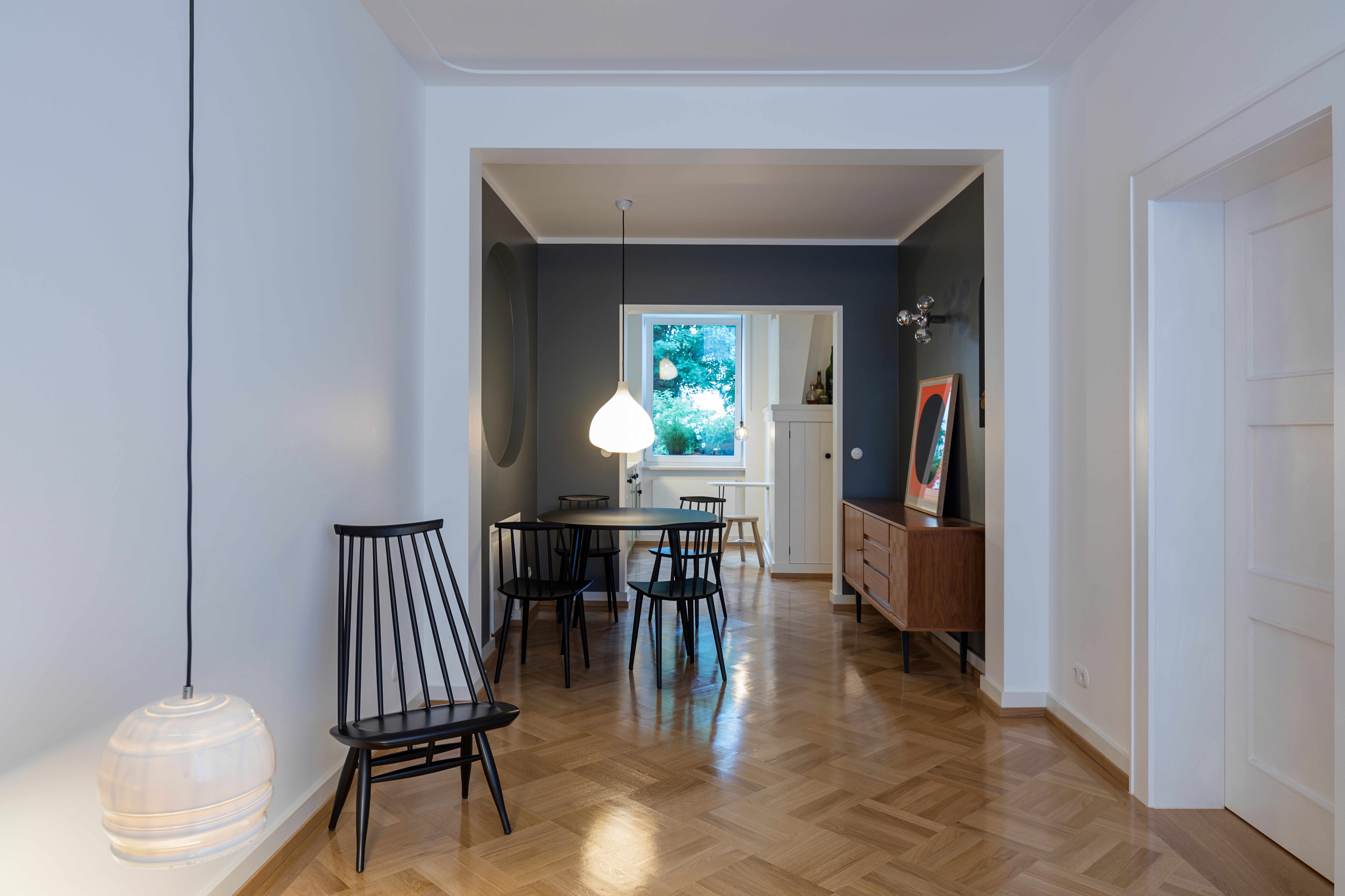 Betrachtet man die Baustellenbilder, wird klar, dass nichts von dem, was heute auf den ersten Blick so selbstverständlich erscheint, vor dem Umbau vorhanden war – nicht das Eichenholzparkett mit seinem klassisch schönen Speckglanz; nicht die vielen praktischen, kleinen und großen Wandnischen; nicht die sanften Stuckaturen der Zimmerdecken und auch nicht die gegliederten Türen ... Wo früher ein Unterzug und Kaminvorsprünge den Raum willkürlich beherrschten, zonieren nun räumliche Einbauten die Wohnung und formen Beziehungen – wie z.B. die Nische am Essplatz zur Tischform – und zum Siebdruck Rupprecht Geigers. Die spielerische Wiederaneignung bekannter und vielfach bewährter Elemente verleiht der Wohnung ihren zeitlosen wie heiteren Charakter.