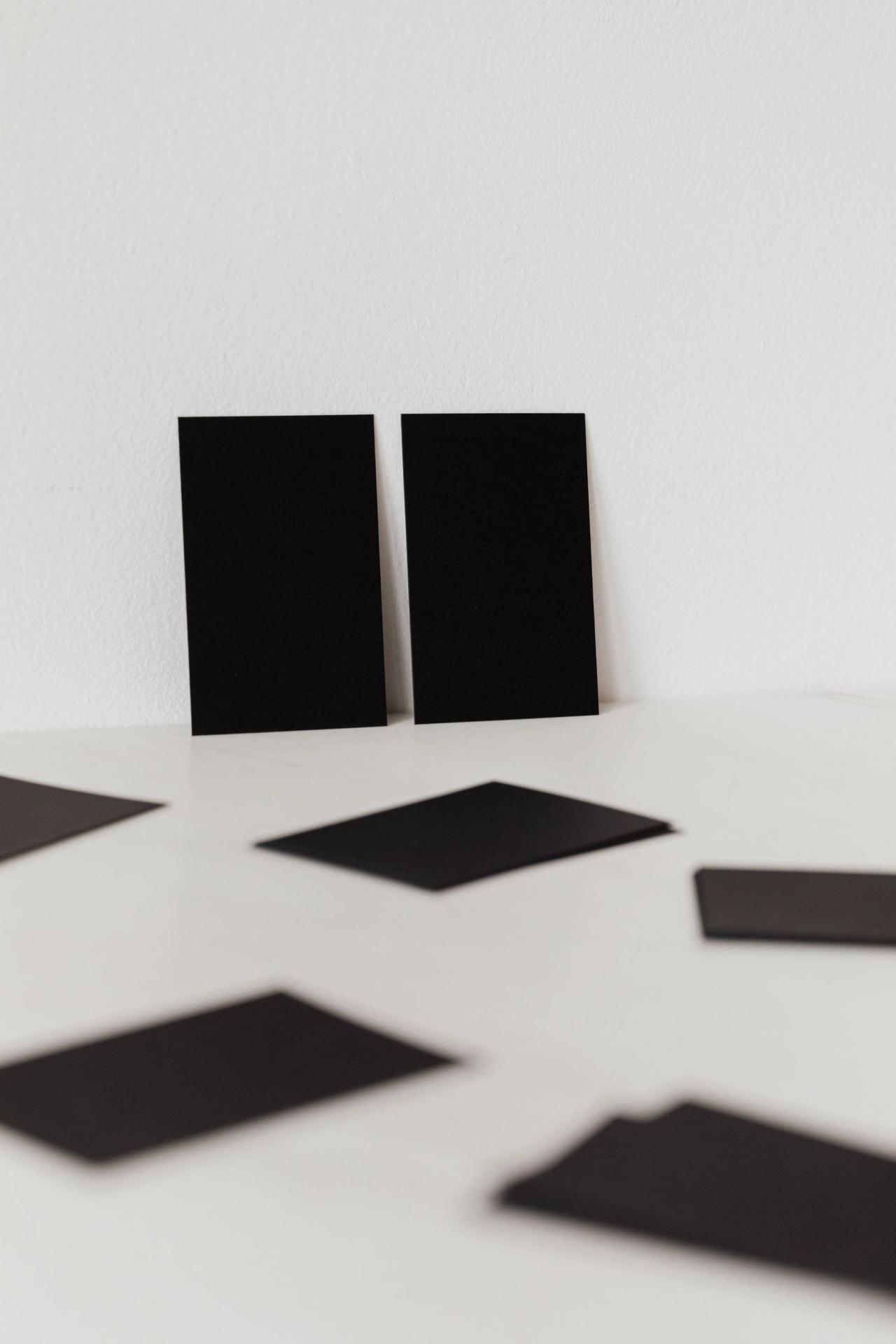 Blank black cards scattered on a white surface.