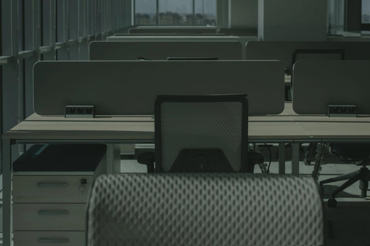 An empty office with rows of desks and chairs.