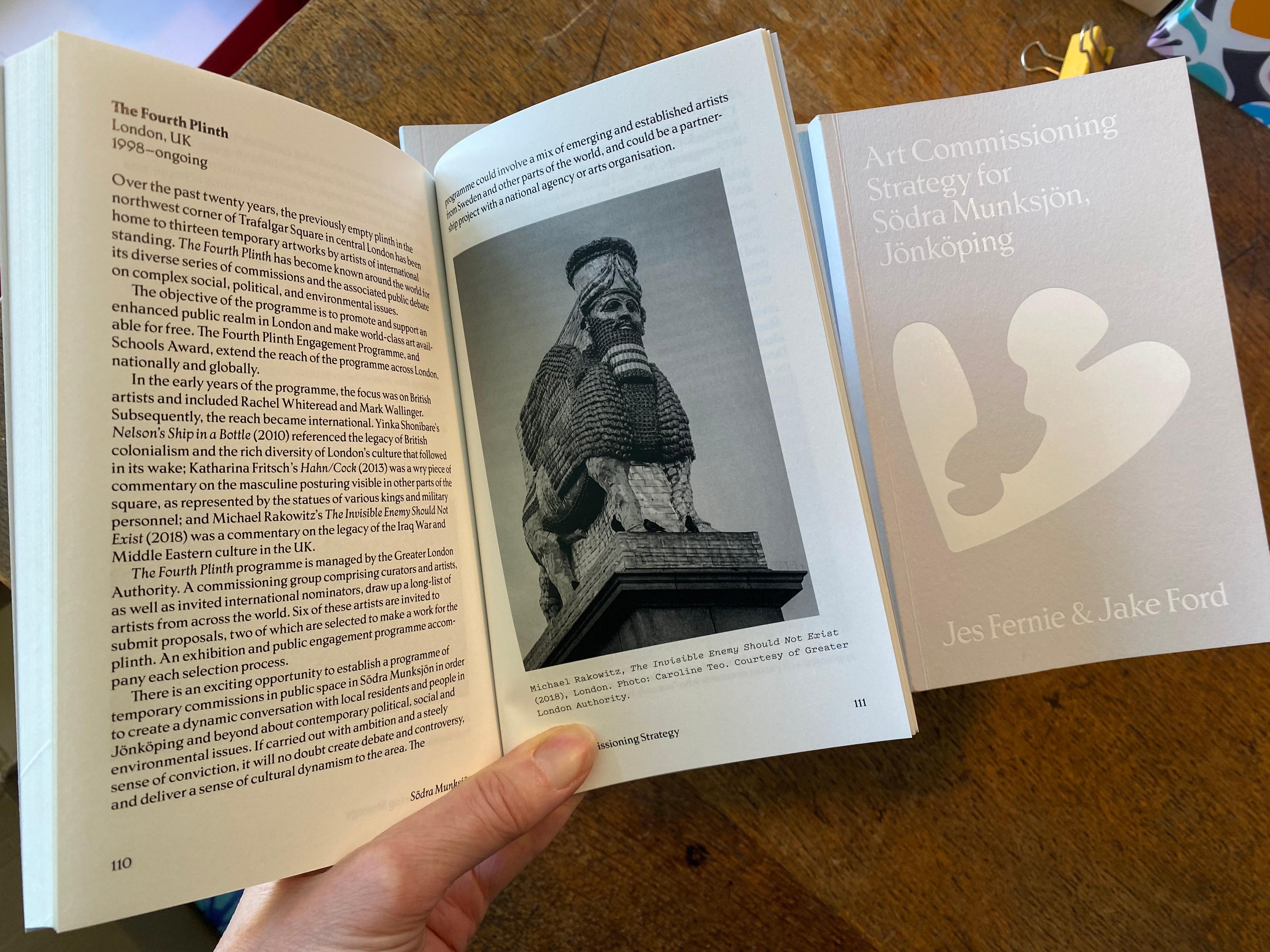 Light gray document cover with the title "Art Commissioning Strategy for Södra Munksjön, Jönköping", a white abstract heart-like graphic in the center, and author names "Jes Fernie & Jake Ford" at the bottom.