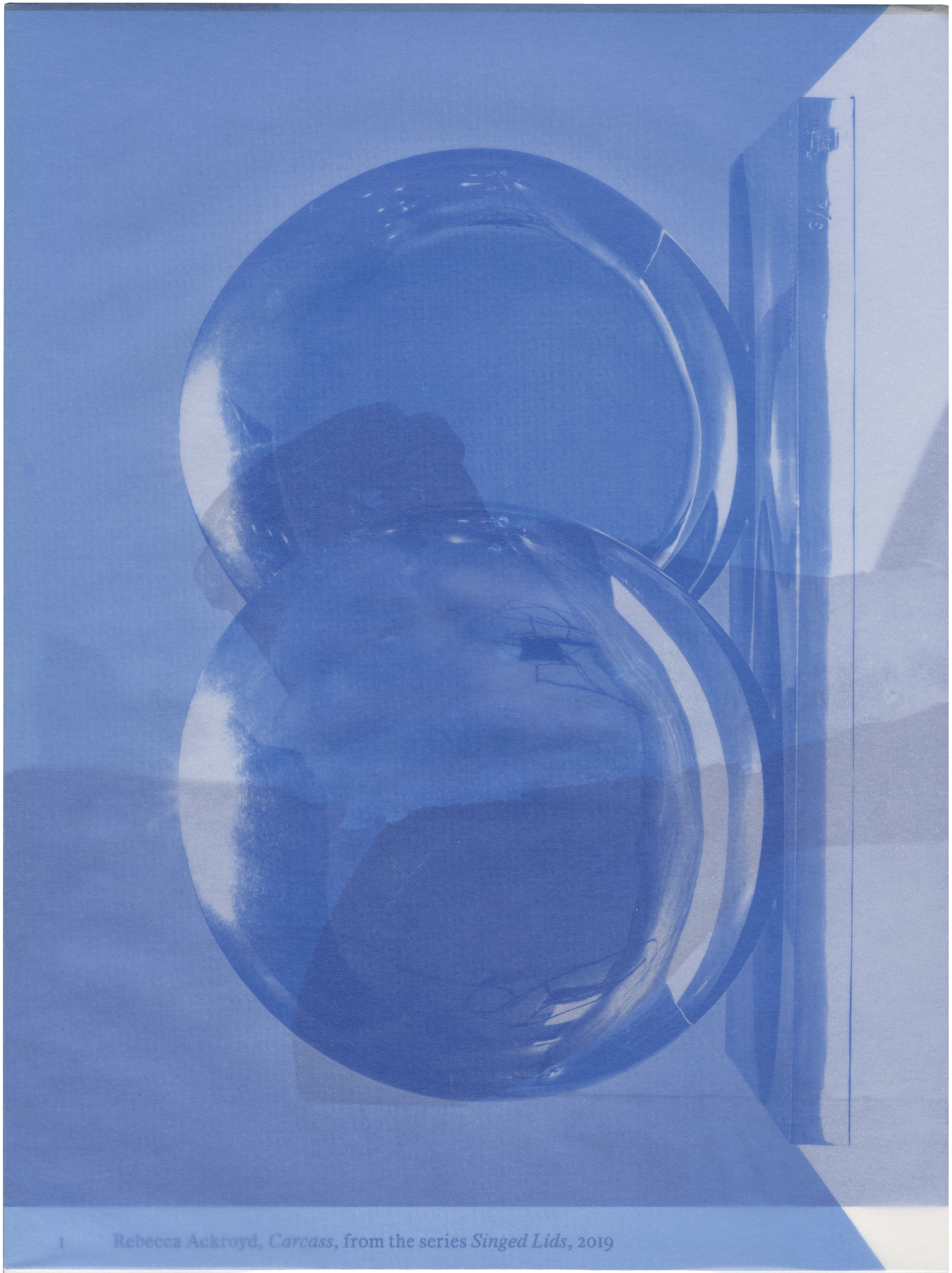 A monochromatic blue image featuring two overlapping circular, reflective objects and a vertical rectangular form to the right.