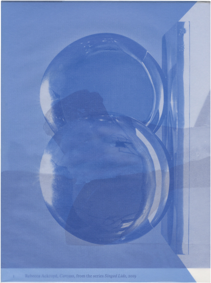 A monochromatic blue image featuring two overlapping circular, reflective objects and a vertical rectangular form to the right.