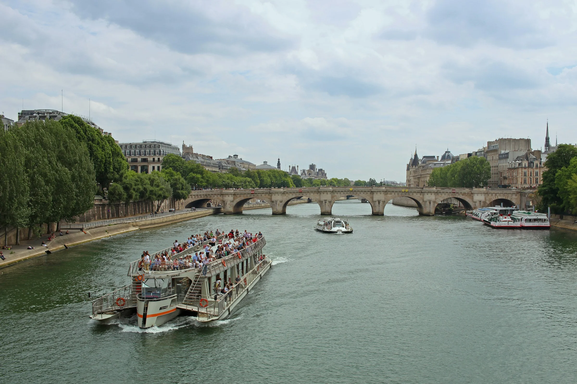 Kapal wisata menyusuri Sungai Seine di Paris dengan jembatan di kejauhan.