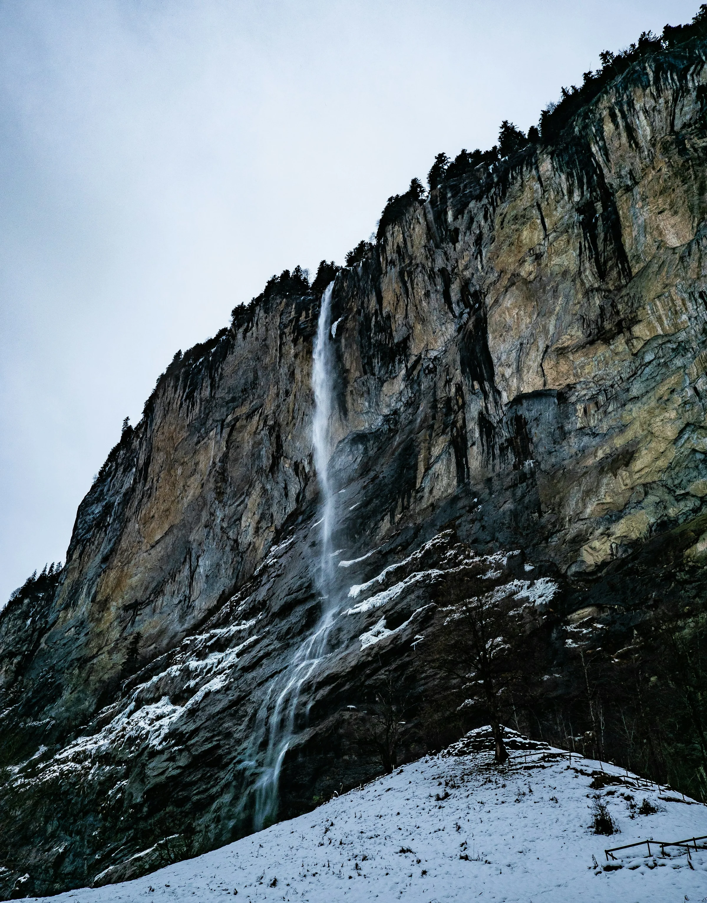 Air terjun Staubbach di Lauterbrunnen dengan salju di kaki tebing.