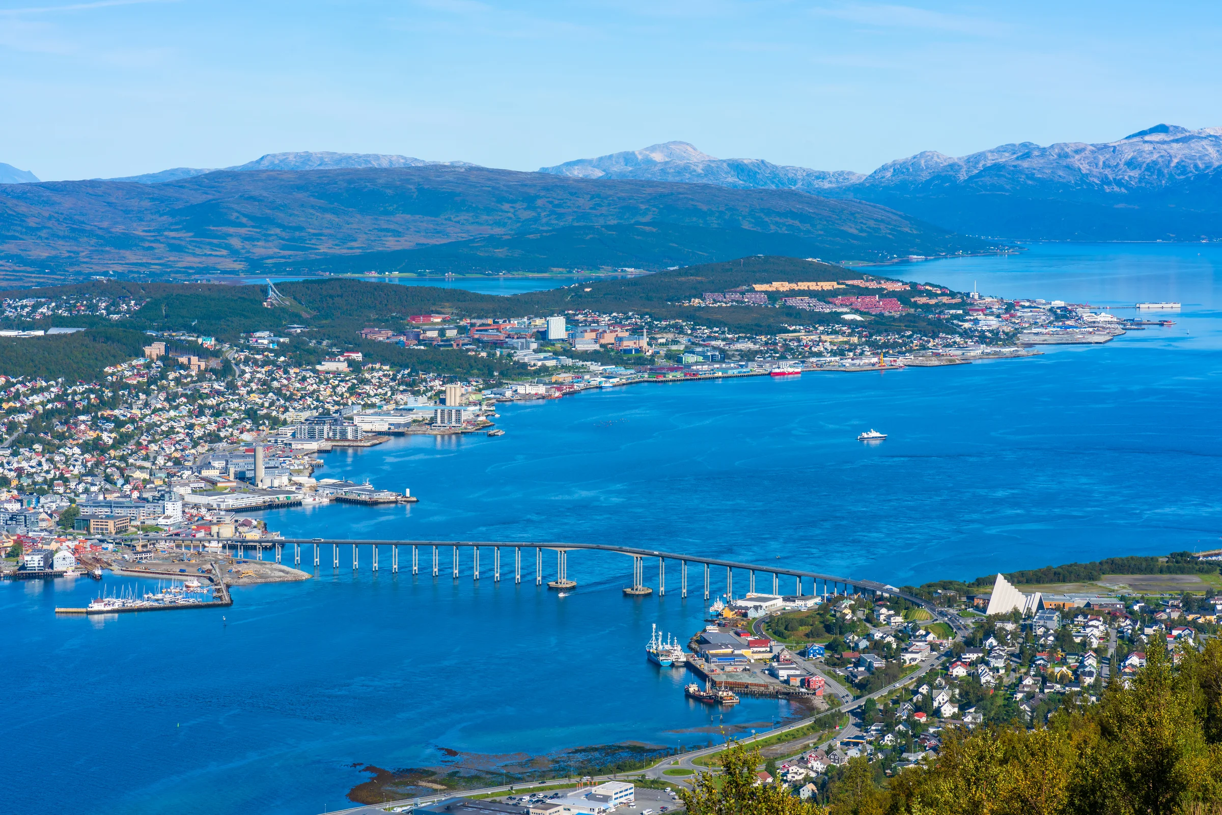 Kota Tromso di tepi fjord dengan jembatan dan pegunungan bersalju di kejauhan