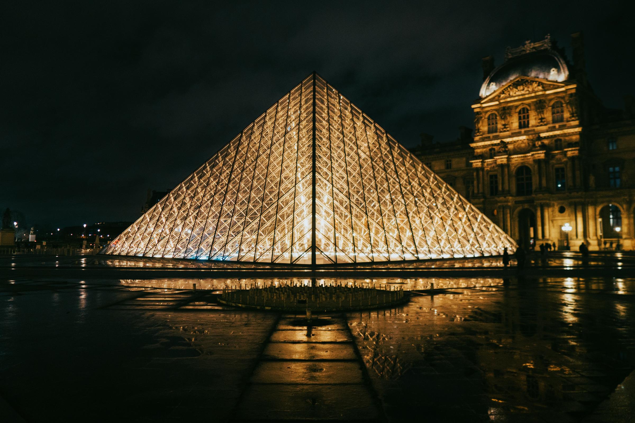 Piramida kaca Louvre menyala keemasan di malam hari Paris