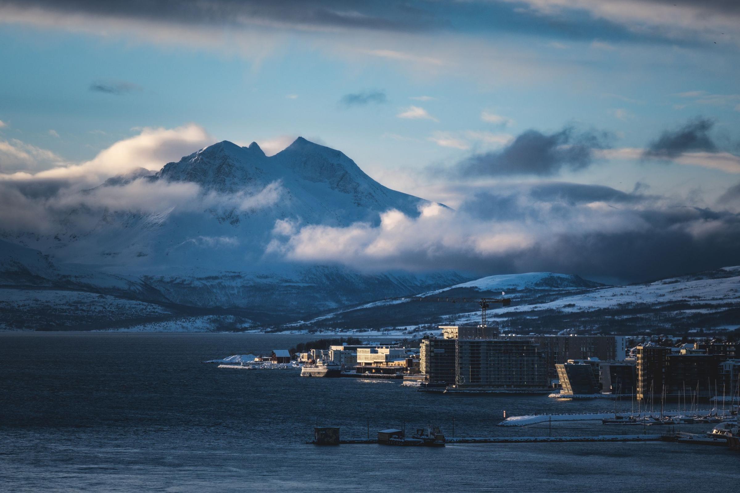Kota Tromso di tepi fjord dengan pegunungan bersalju, Norwegia.