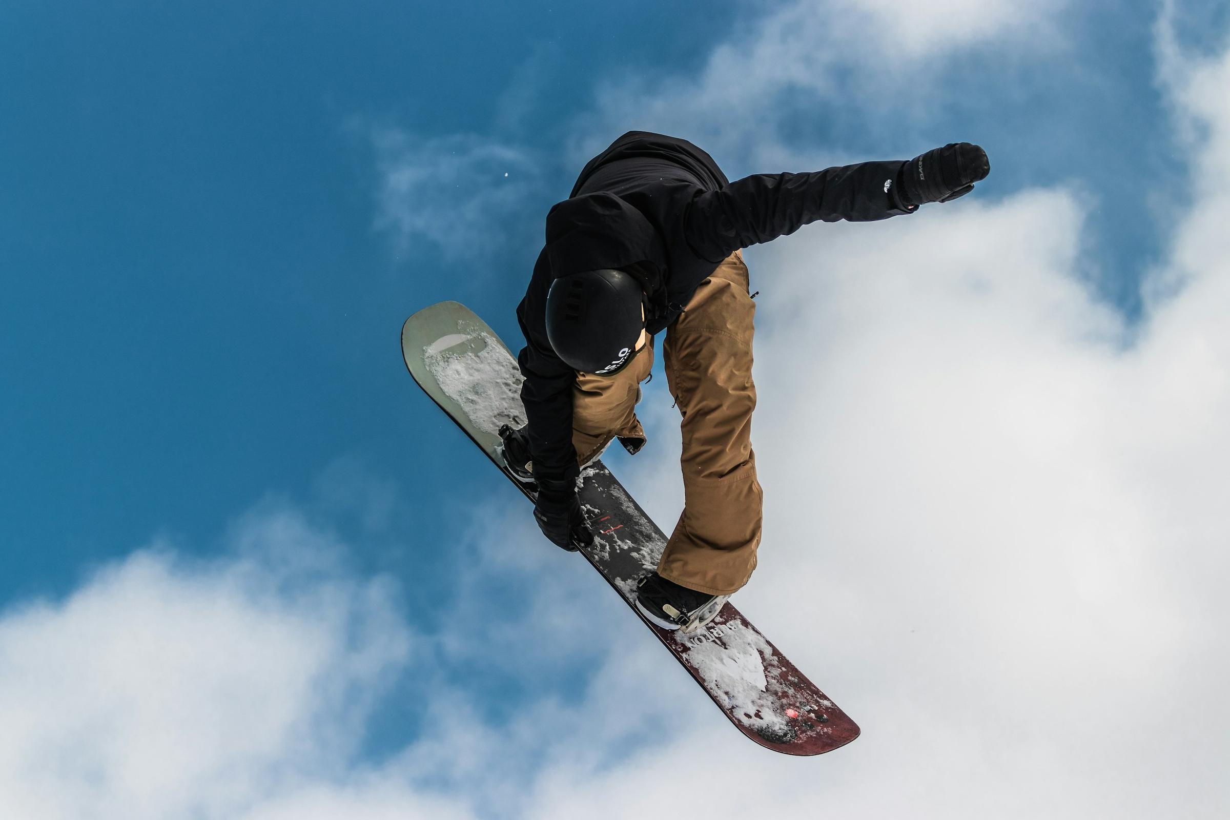 Snowboarder melompat di udara dengan latar langit biru, olahraga salju musim dingin
