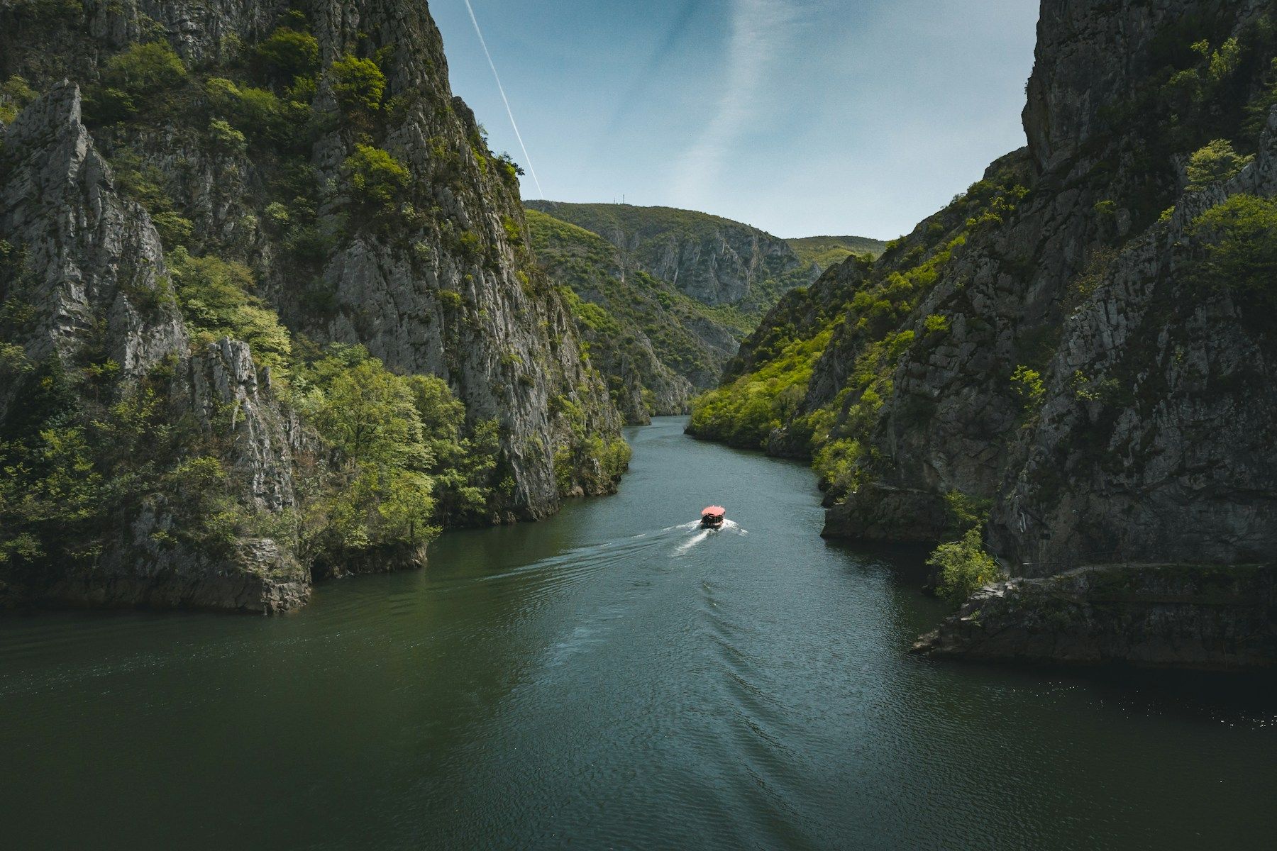 Perahu kayu menyusuri Matka Canyon, kanyon dramatis di Makedonia Utara dengan air berwarna toska