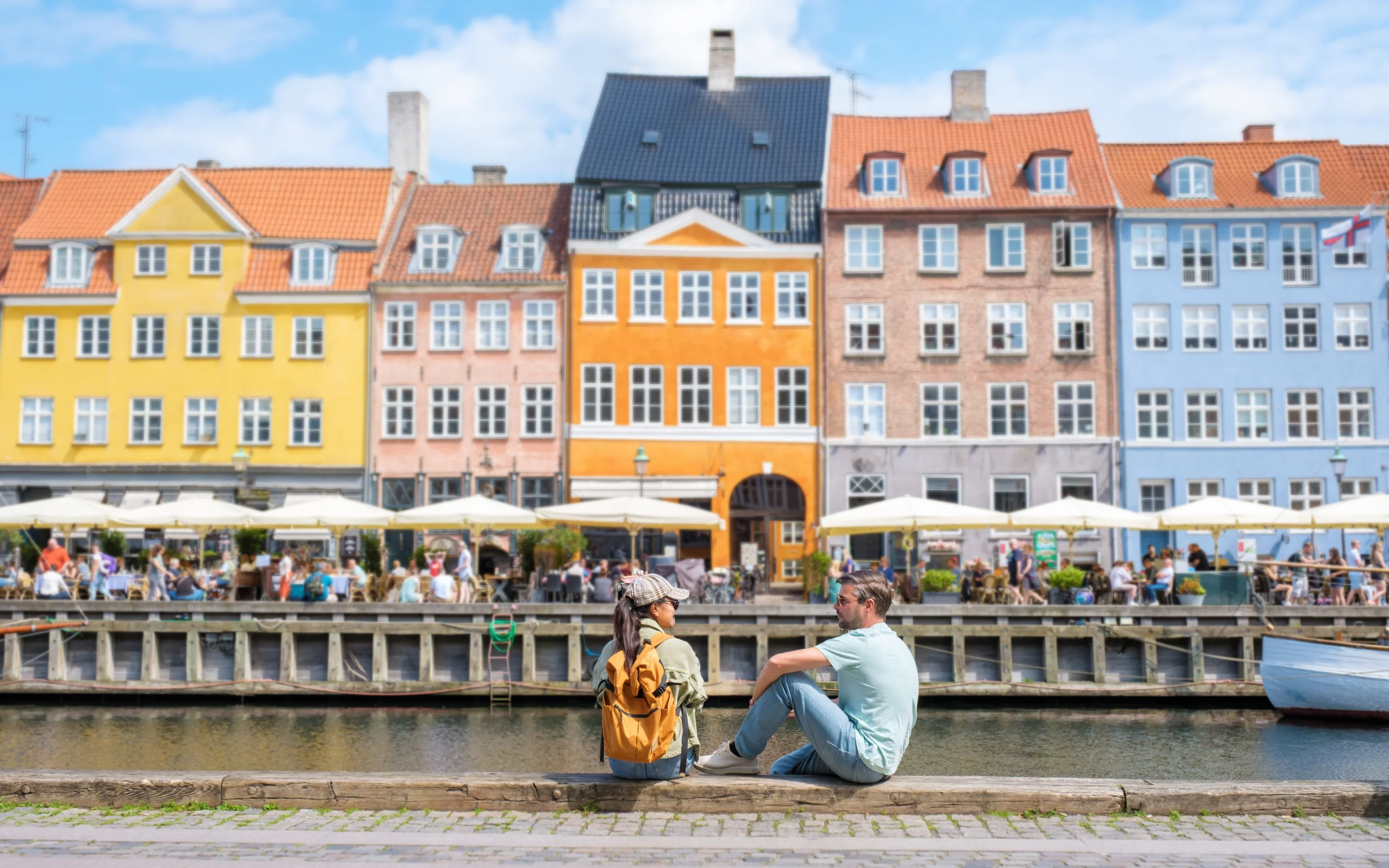 Rumah warna-warni tepi kanal Nyhavn di Copenhagen dengan kafe di sepanjang dermaga