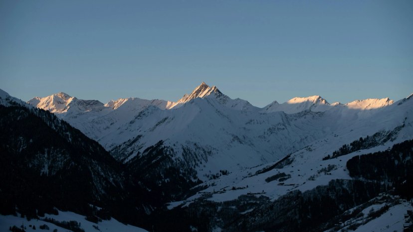 Desa pegunungan Swiss tertutup salju tebal di bawah langit biru cerah musim dingin.