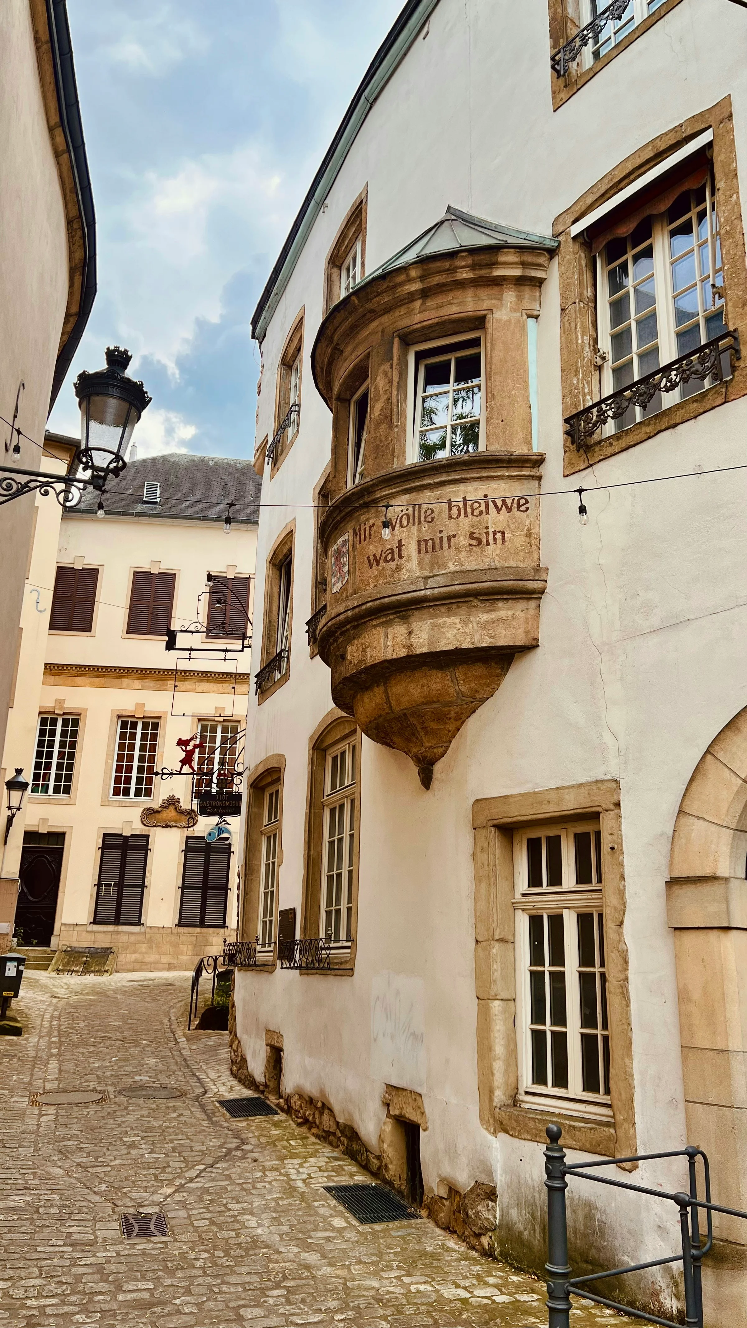 Gang kota tua Luxembourg dengan jendela oriel batu dan lampu jalan klasik.