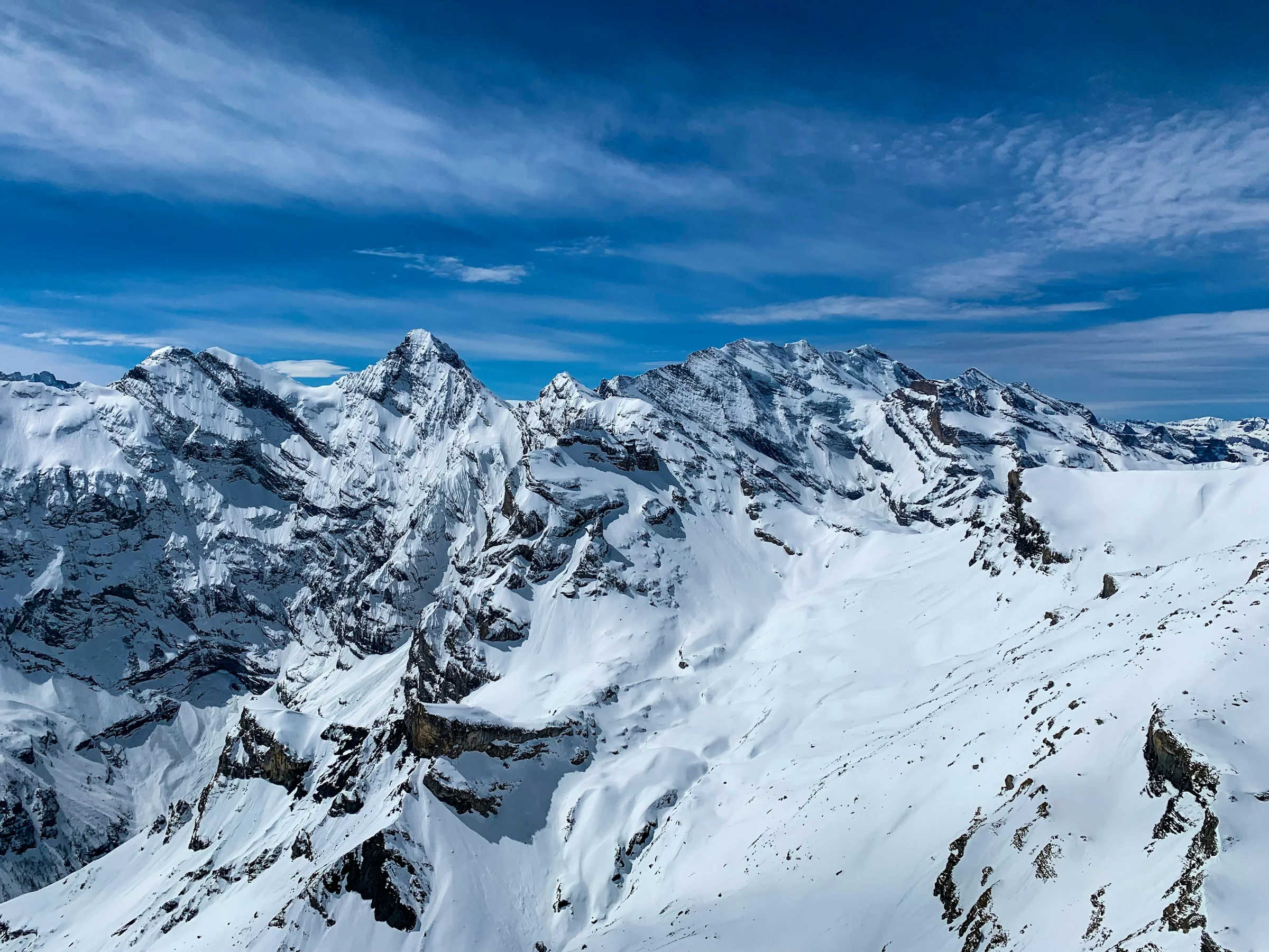 Puncak-puncak pegunungan berselimut salju di bawah langit biru tua, Alpen Swiss.