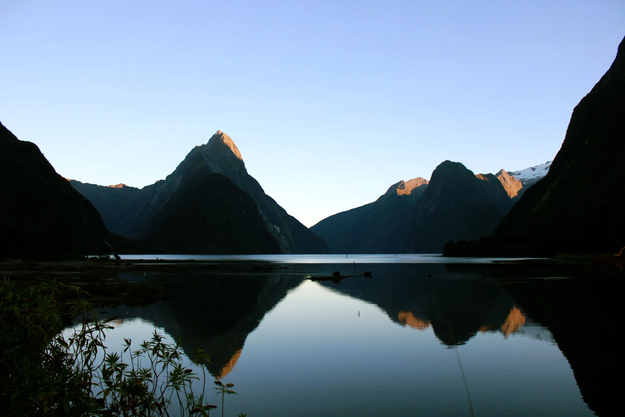 Puncak Mitre Peak menjulang di atas perairan tenang Milford Sound Selandia Baru saat senja