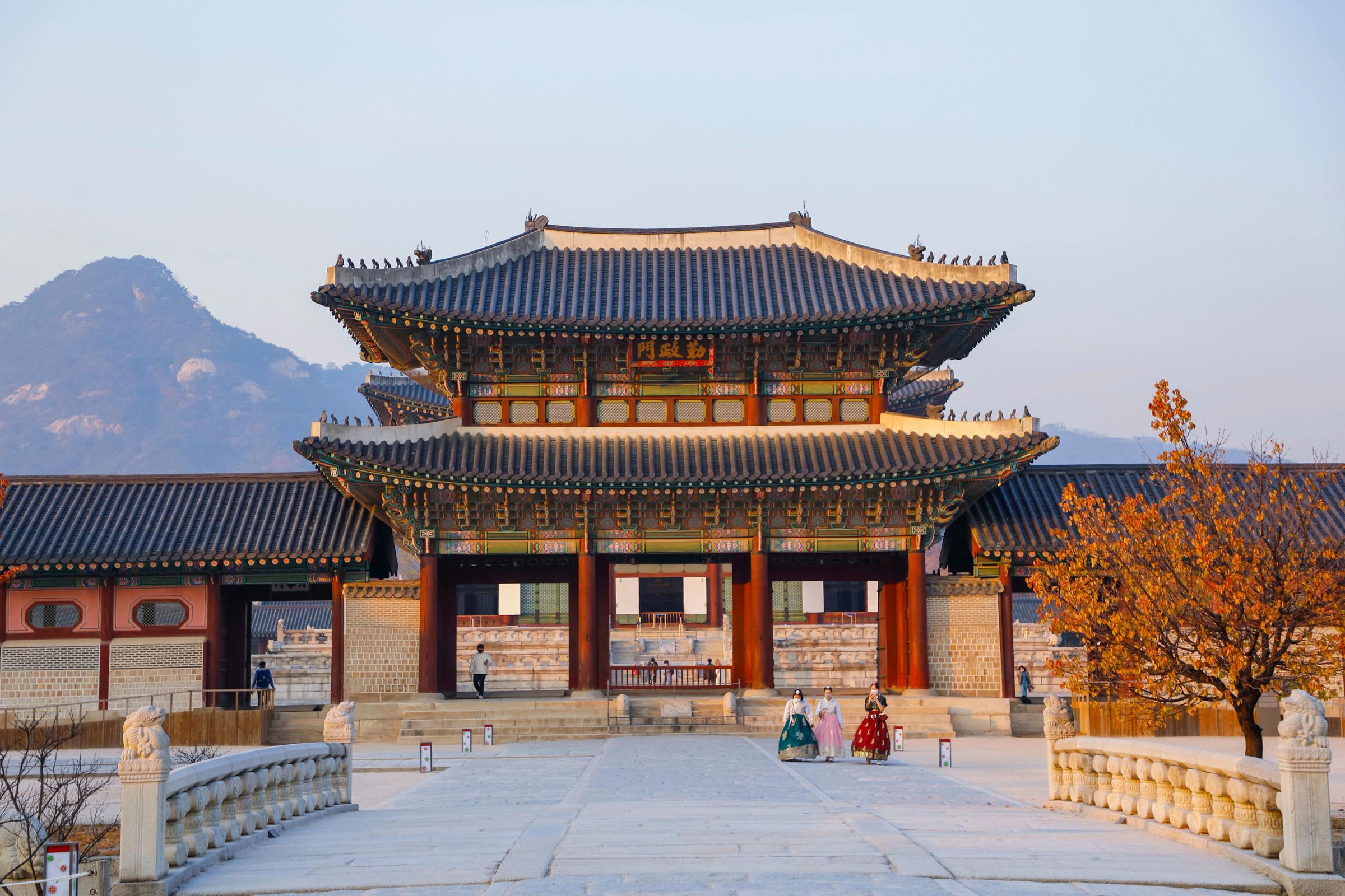Gerbang Istana Gyeongbokgung Seoul bermandi cahaya keemasan sore dengan latar gunung