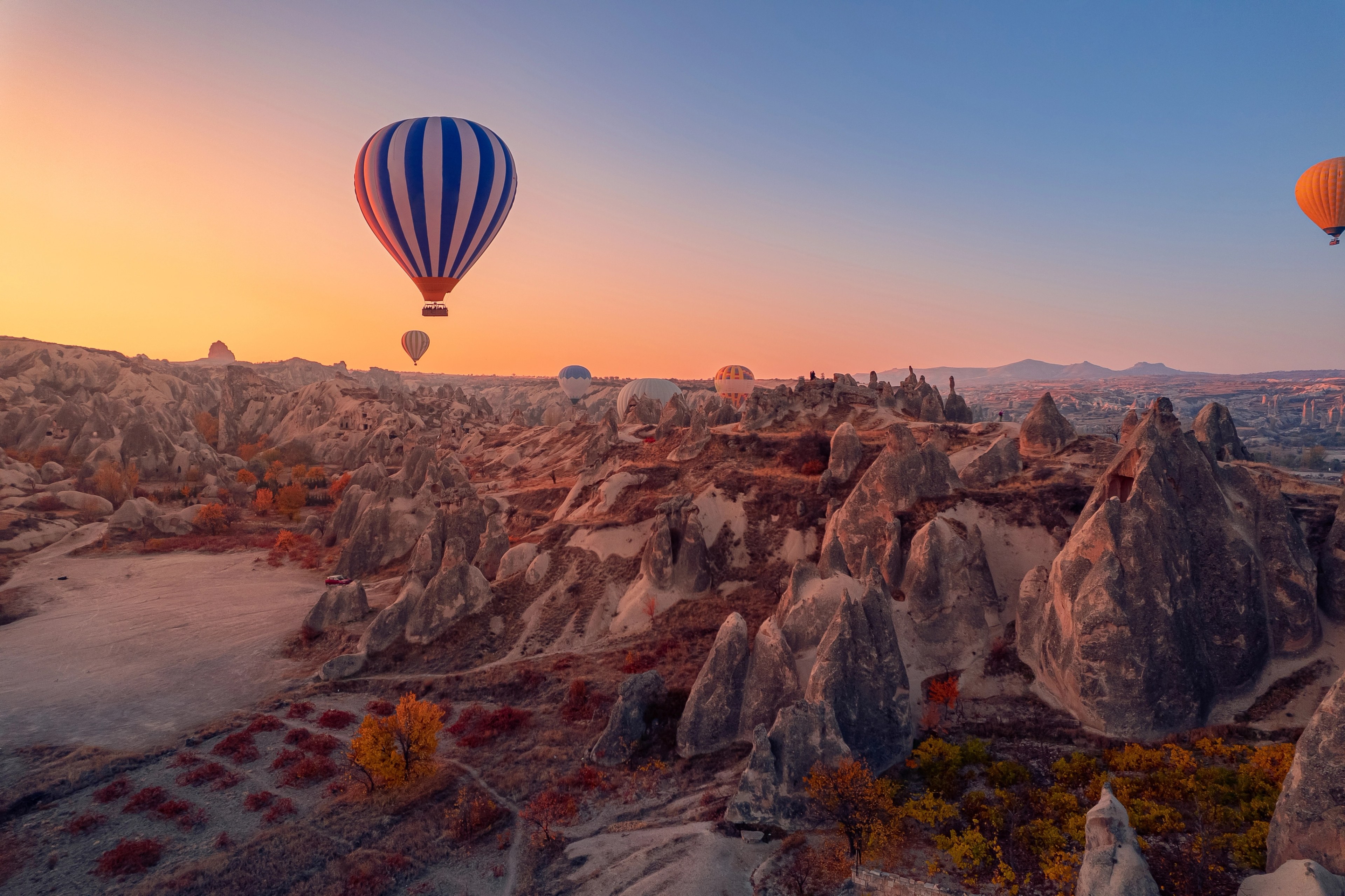 Balon udara terbang di atas lanskap Cappadocia saat matahari terbit, Turkiye